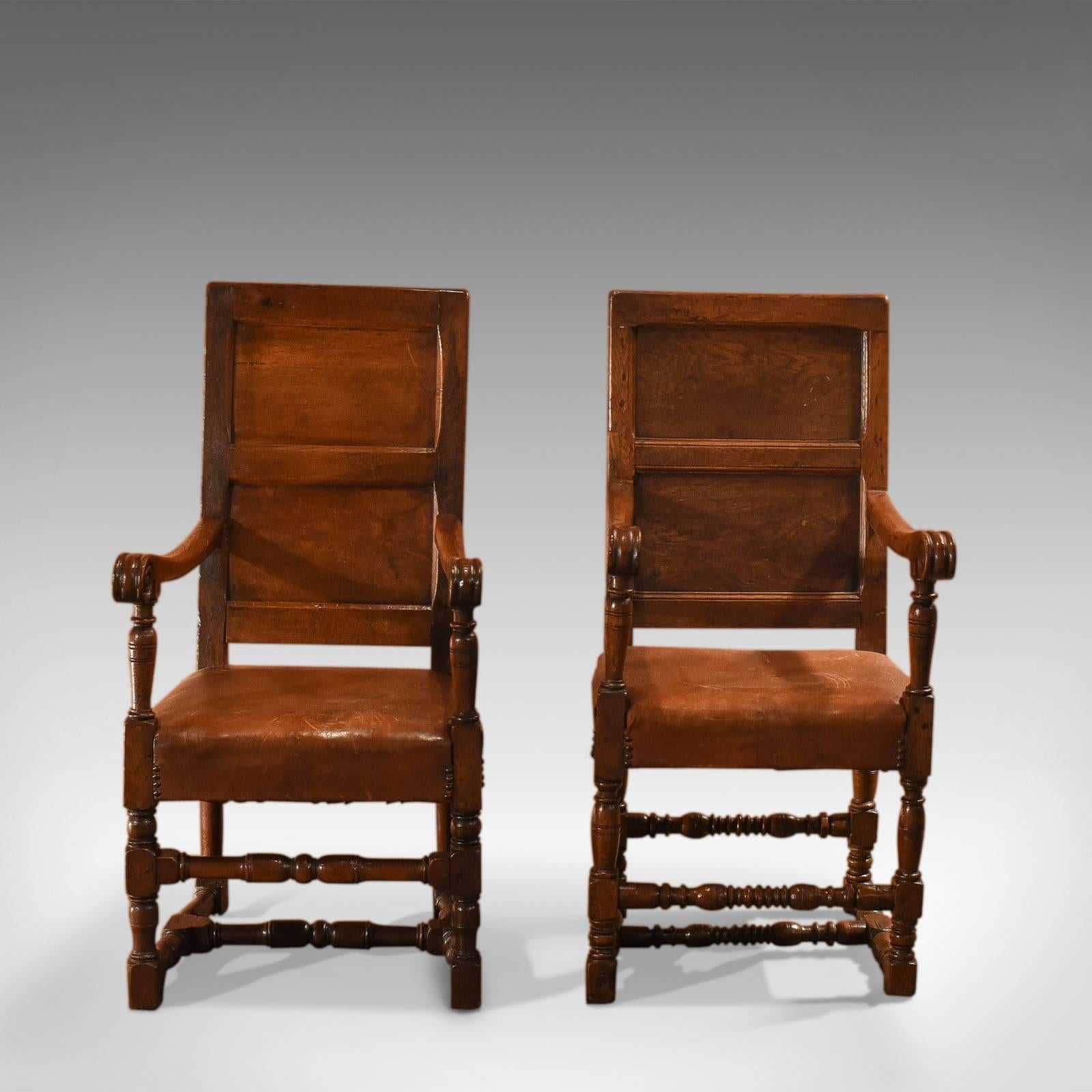 This is a pair of similar antique, 18th century and later panel back armchairs.

The aged English oak carries a warmth and deep lustrous shine. Raised on turned legs united by ring turned stretchers the shaped arms terminate in scrolled ends,