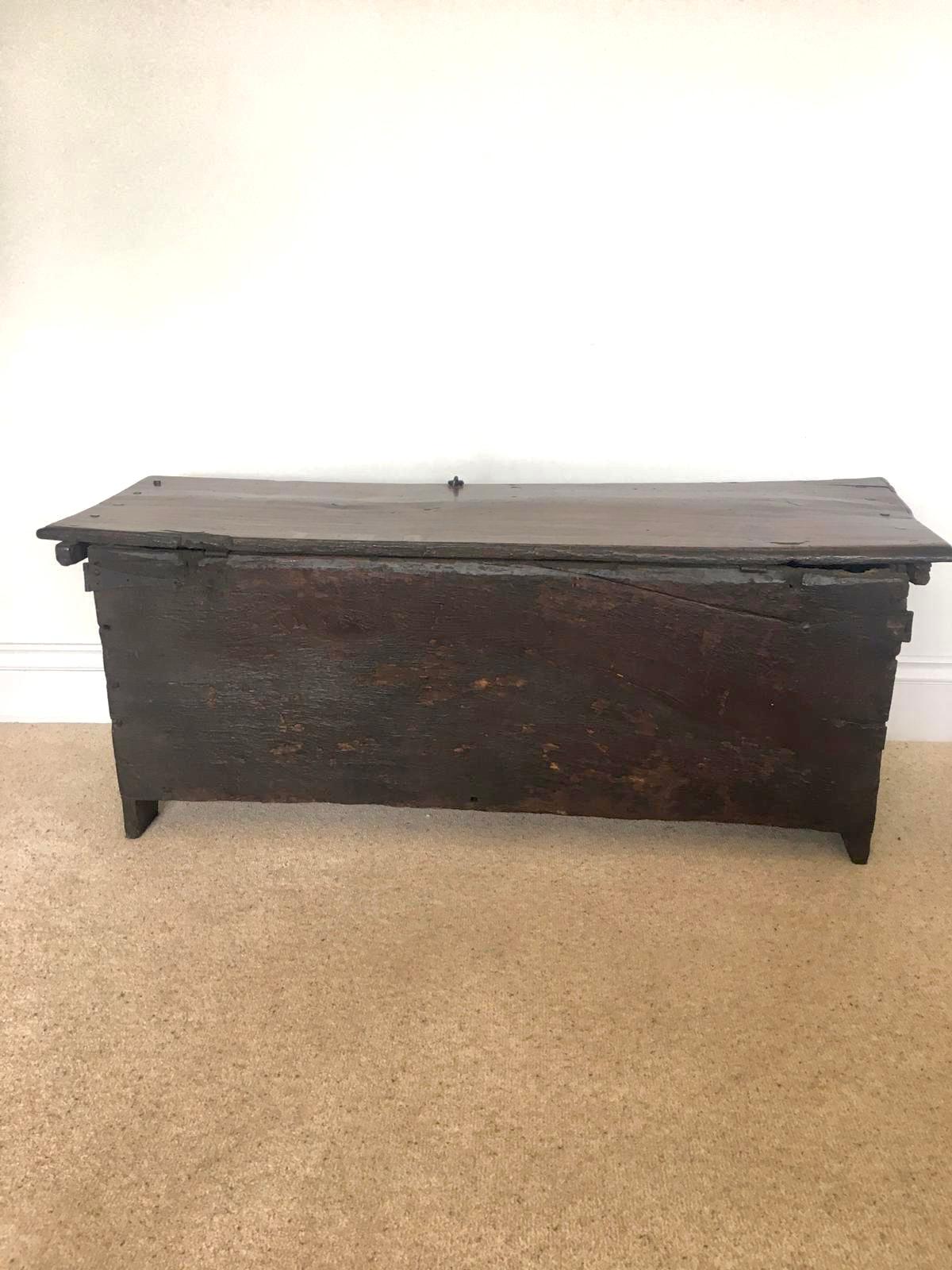 18th century antique carved oak coffer having a lift up plank top lid with a moulded edge opening to reveal a storage compartment. It boasts a quality carved frieze with an original iron lock plate, three magnificently carved oak panels depicting