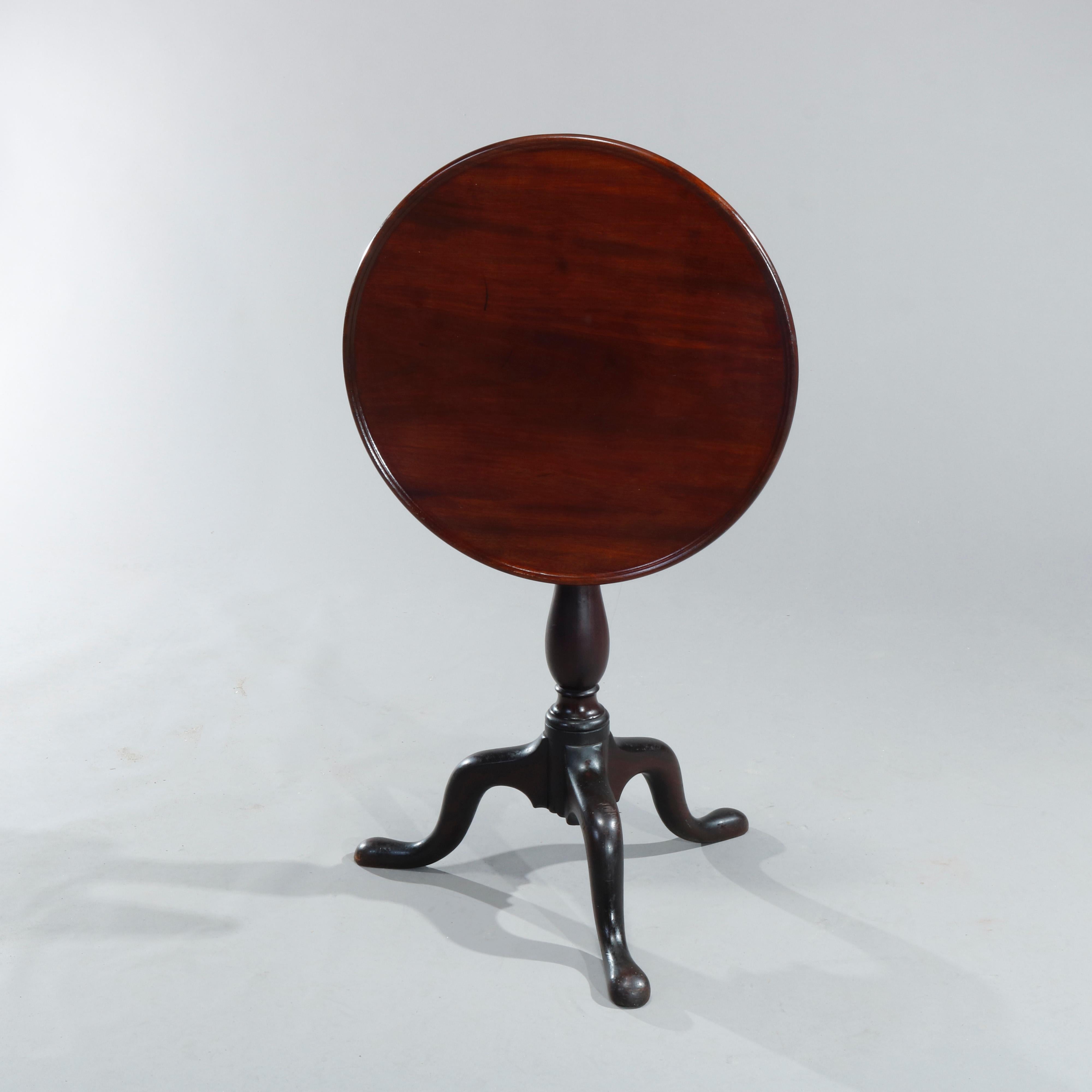 An antique 18th century English Queen Anne tilt top table offers mahogany construction with round top surmounting birdcage tilt top support and over turned column, raised on cabriole legs terminating in pad feet, c1770

Measures: 27.5
