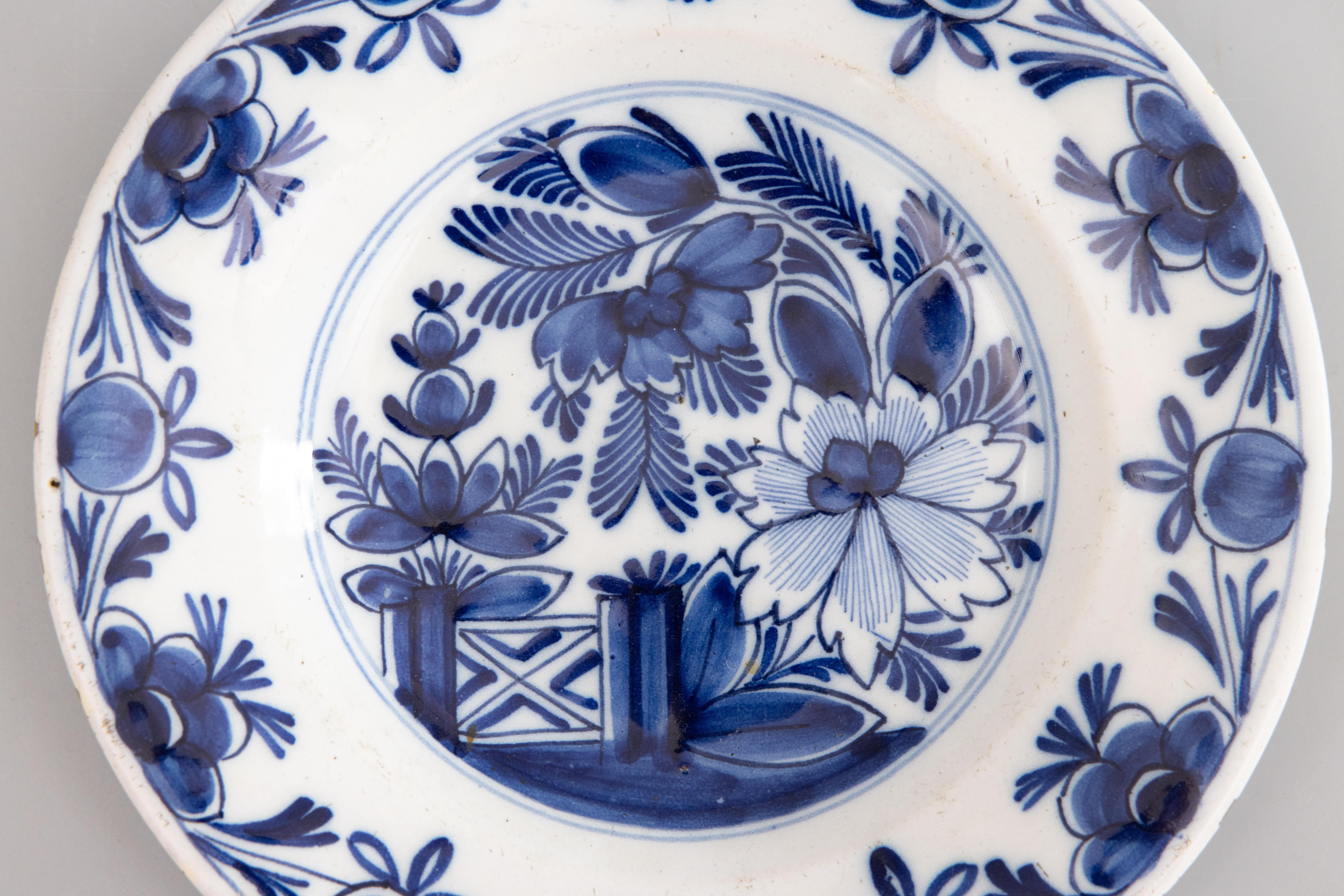 Ein schöner antiker Teller aus Delft mit einem auffälligen Blumenmuster und einem Gartentor in der Mitte, umgeben von einem Blumenmotiv am Rand. Alle handbemalt in leuchtendem Kobaltblau.

ABMESSUNGEN
9.25ʺW × 1.38ʺD × 9.25ʺH