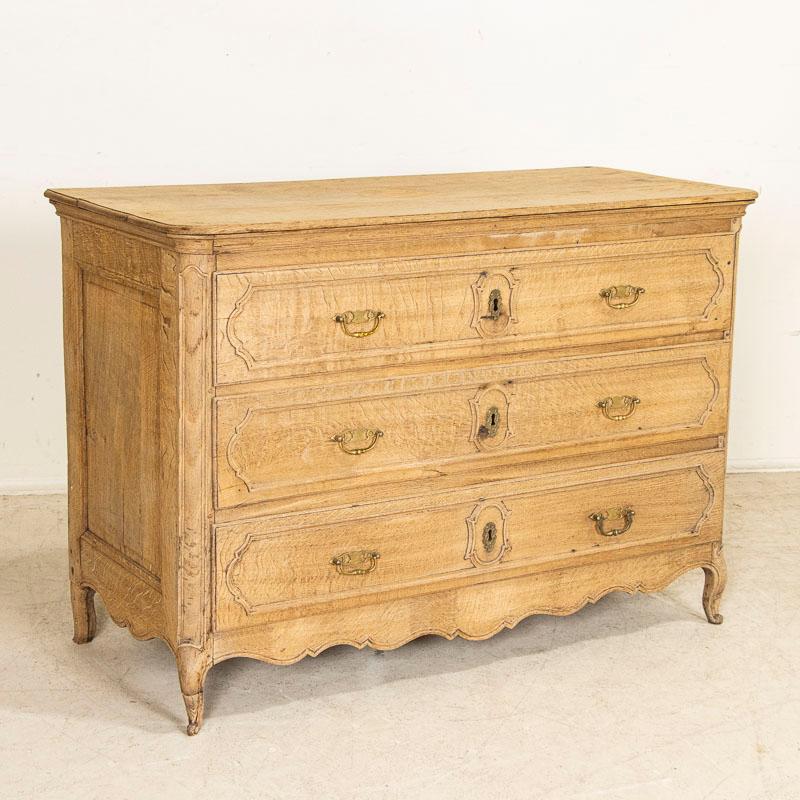 This handsome large French oak chest of drawers has been given new life with a bleached finish, lightening the dark oak and bringing out the lovely details of the paneled drawers and cabriolet feet. Notice the eye-catching unique grain revealed