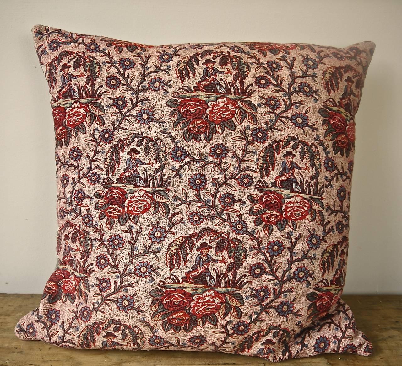 French late 18th century from Bolbec block printed cotton cushion with a charming print of a man in a blue suit and striped stockings with a bird on his hand and a dog by his side. He is surrounded by an arching tree and a clusters of flowers on a