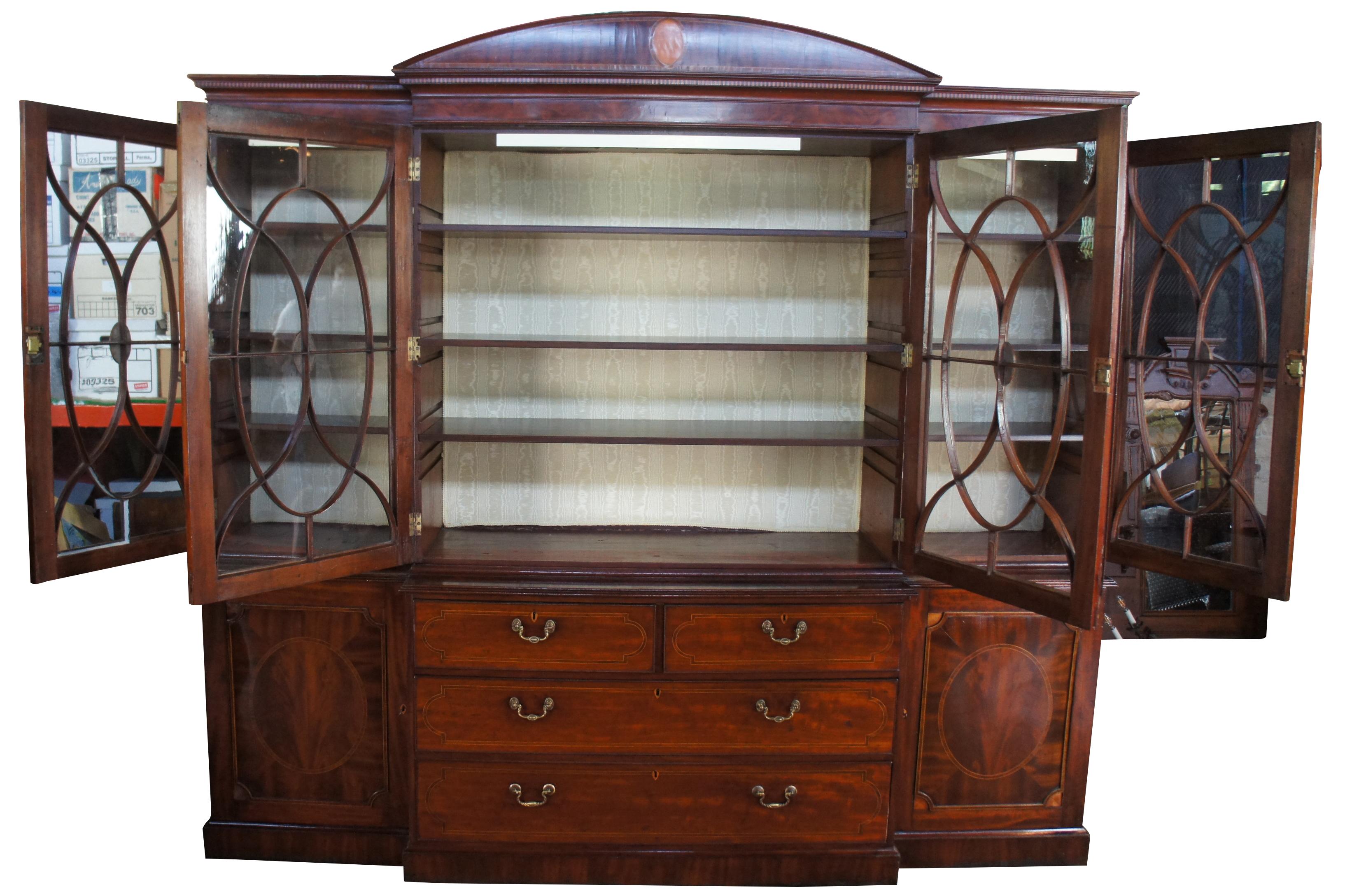 Monumental 18th century George III English breakfront. Made from mahogany with oval burled panels and yew inlay. Features original glass with intricate fretwork. Opens to three adjustable shelves and a silk backing. Includes 4 drawers with banding.