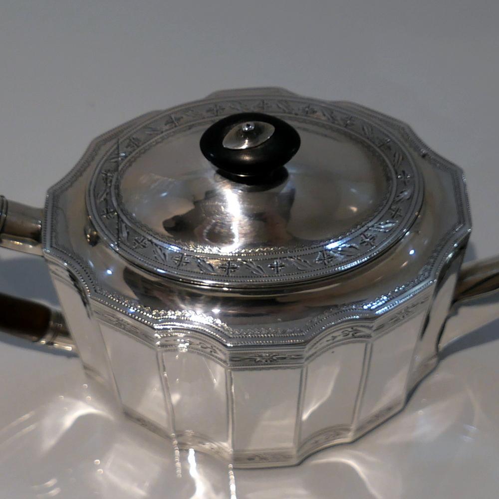 A beautiful 18th century silver shaped oval (paneled) teapot decorated with elegant bands of intricate bright cut hand engraving. The spout is of the highly desirable ‘straight’ formed and the fruitwood handle is scroll design. The slight doming of