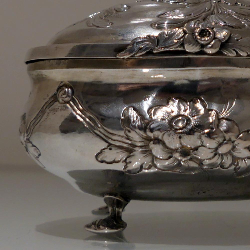 A beautiful 18th century German oval silver sugar box decorated with elegant embossed floral garlands around the centre of the body. The box sits on four stylish cast wire feet and the domed hinged lid has additional floral embossing for