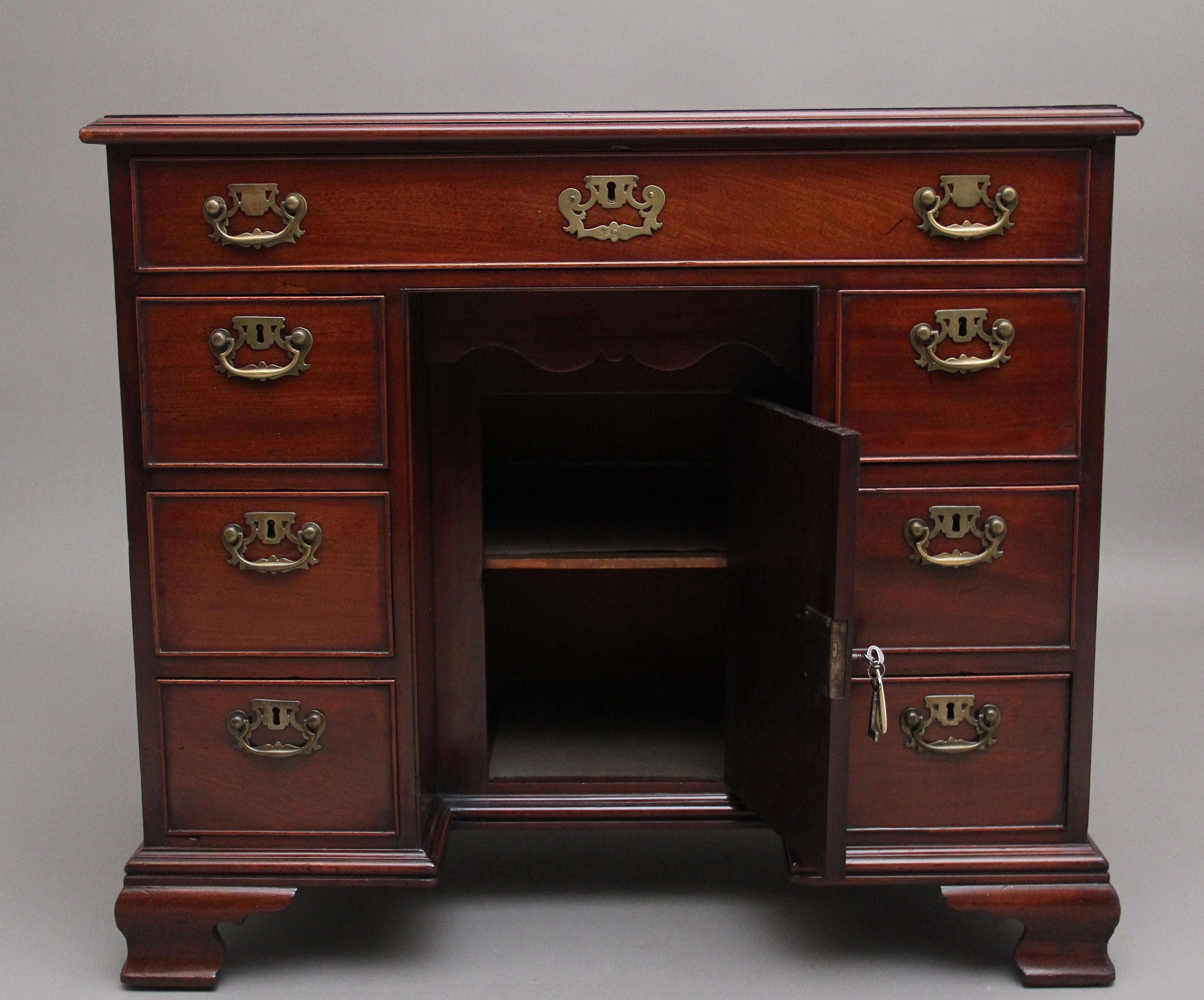 18th Century mahogany kneehole desk, having a wonderfully figured moulded edge top above a selection of seven drawers with the original brass plate handles and escutcheon, hinged cupboard door at the centre within the kneehole and a single