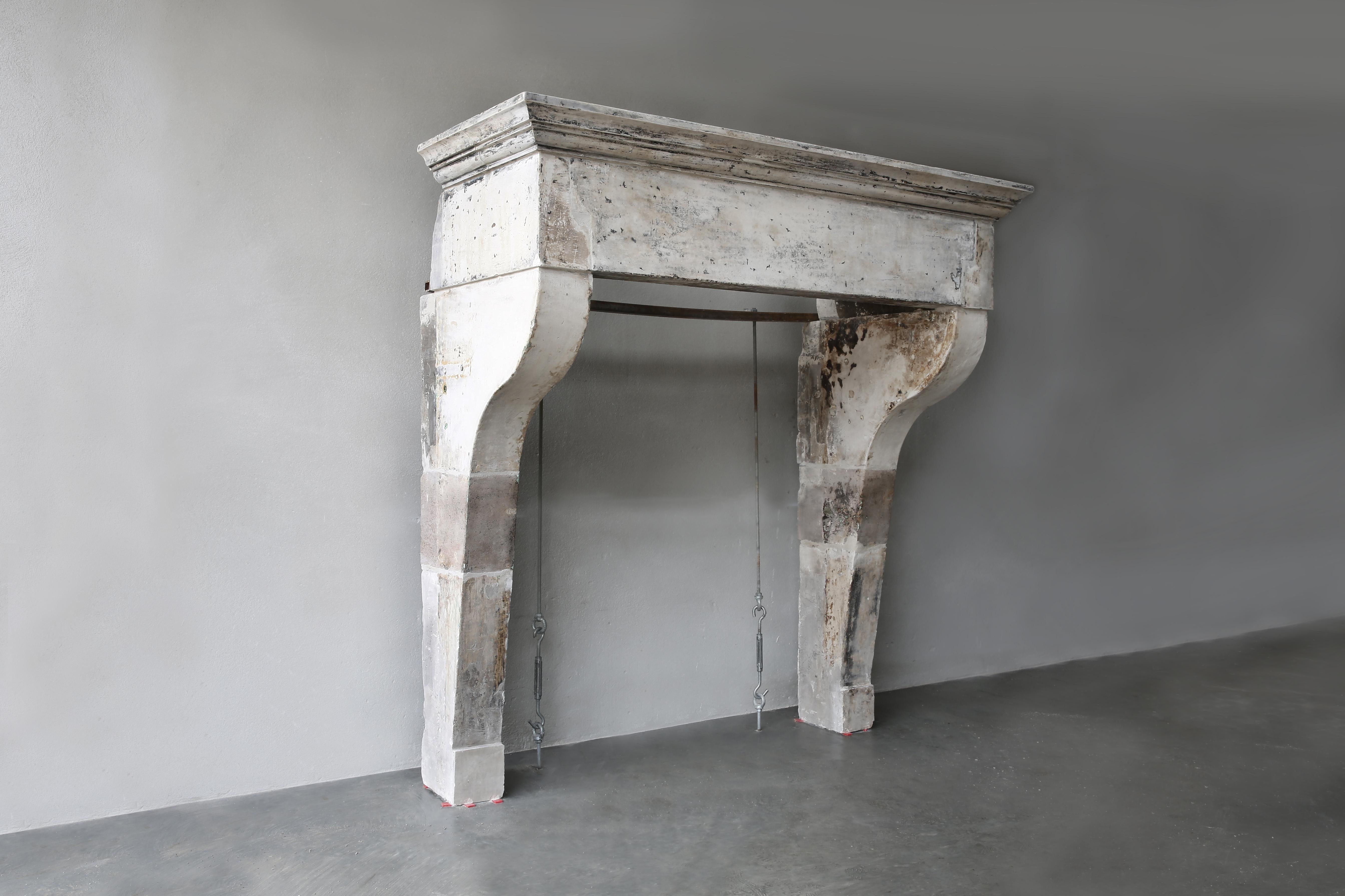 Antique fireplace of French limestone from the 18th century in Campagnarde style. This one comes from Beaune in France. A beautiful robust fireplace with a wide top and slender legs that are slightly curved. This robust fireplace has a rural design