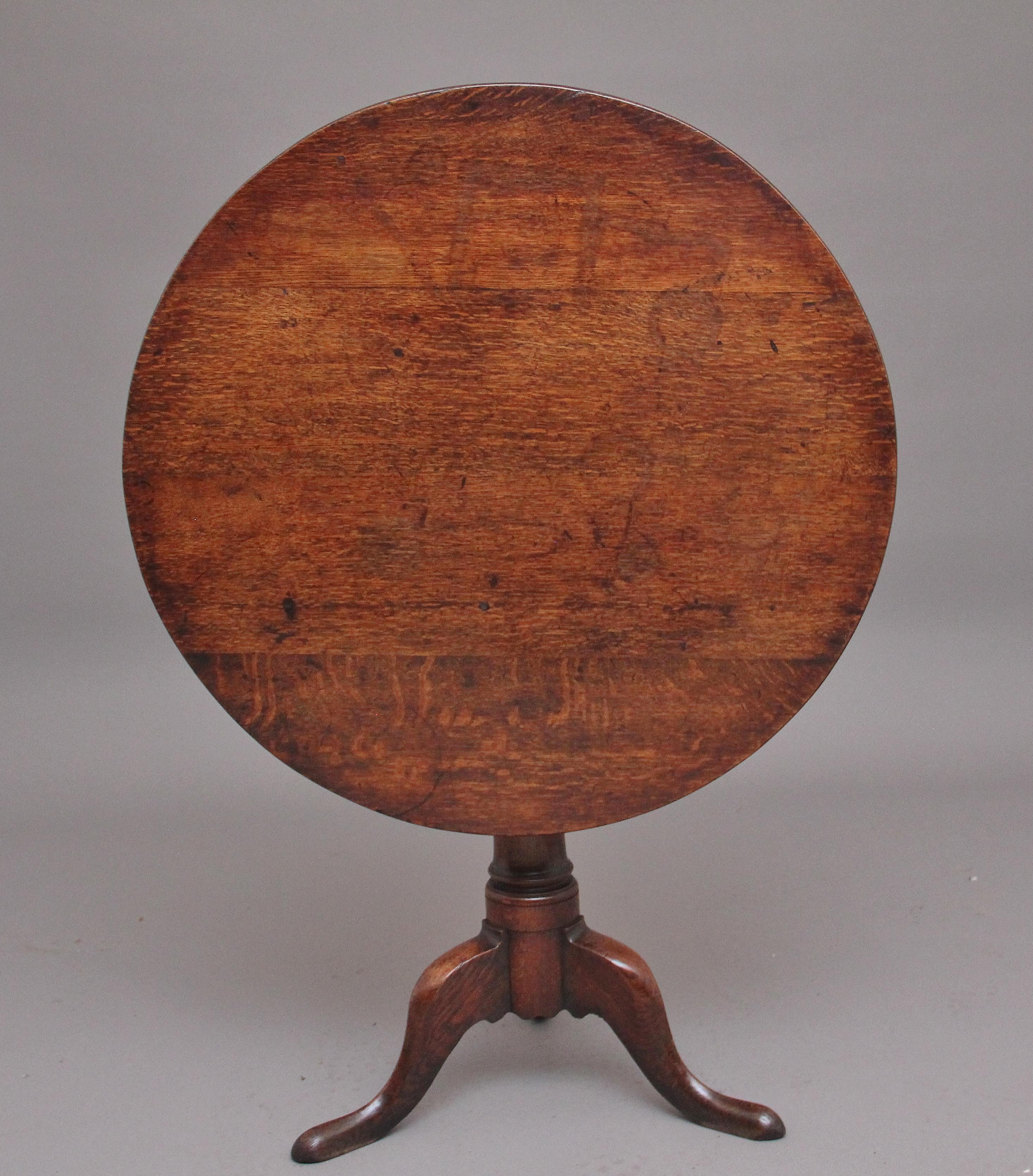 18th Century oak tripod table, having a wonderful figured circular top which sits on a birdcage mount so you can turn the top without turning the base, supported on a turned column terminating with three slender shaped legs. Lovely warm oak colour