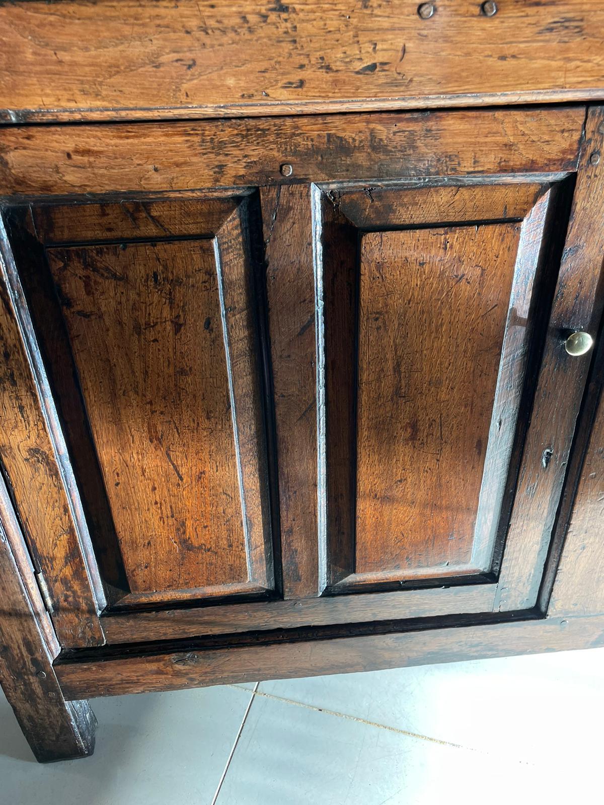 18th century antique quality oak dresser base having a quality oak top above three drawers with a moulded edge and brass knobs above a pair of panelled doors opening to reveal a shelf interior 

The colour and aged patination of this quality piece