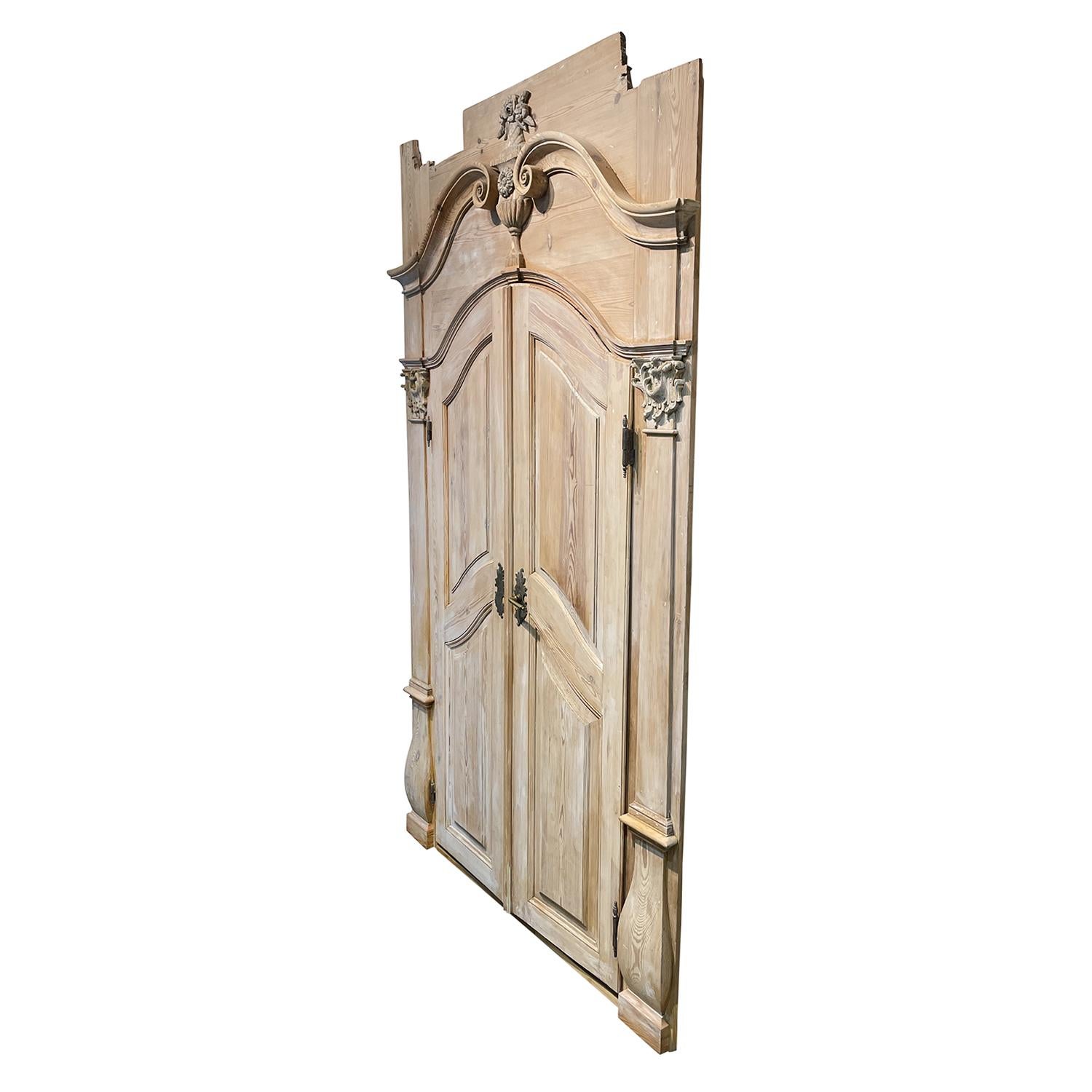 An antique Austrian Baroque entrance door made of hand crafted Pinewood, in good condition. The restored double-door from Salzburg is consisting its original hardware and key. Minor fading, scratches due to age. Wear consistent with age and use.