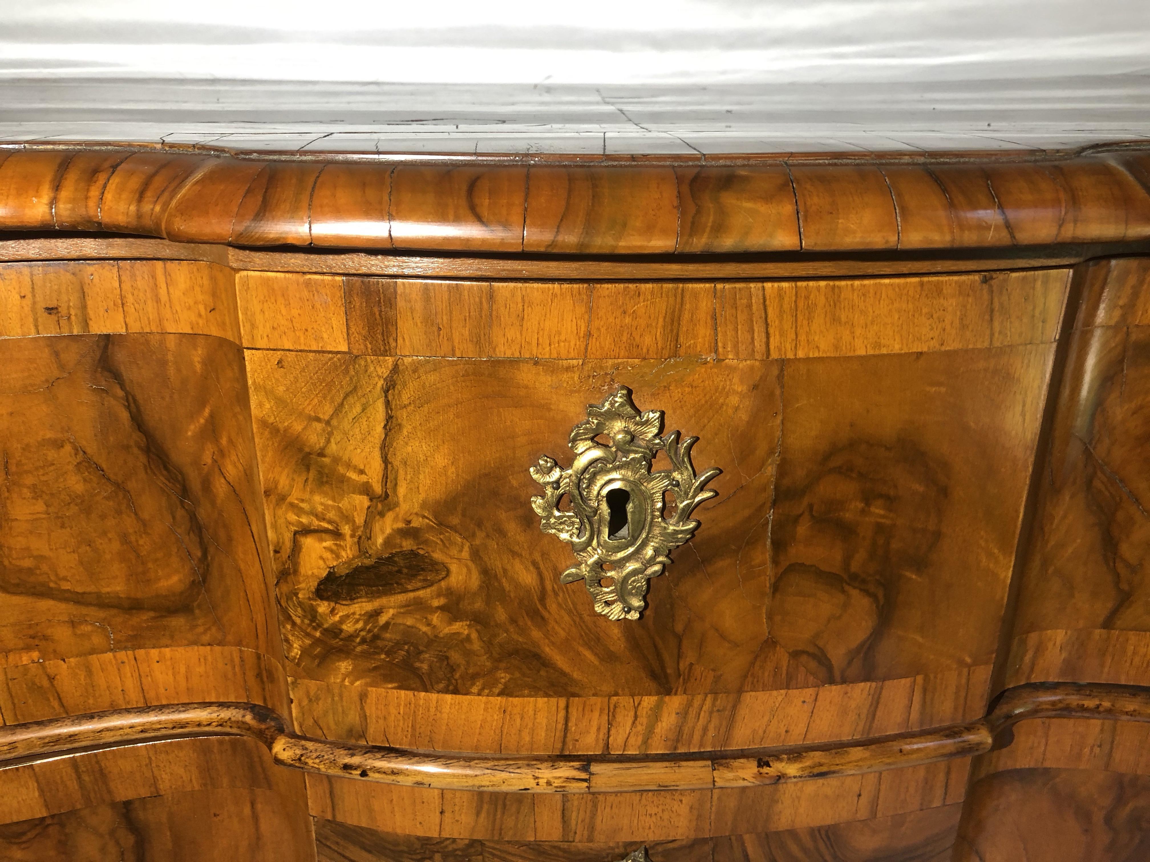 Mid-18th century high gloss Rococo walnut serpentine front, gilt bronze mounted three-drawer chest with bracket feet, original hardware, and satiny lustrous patina.