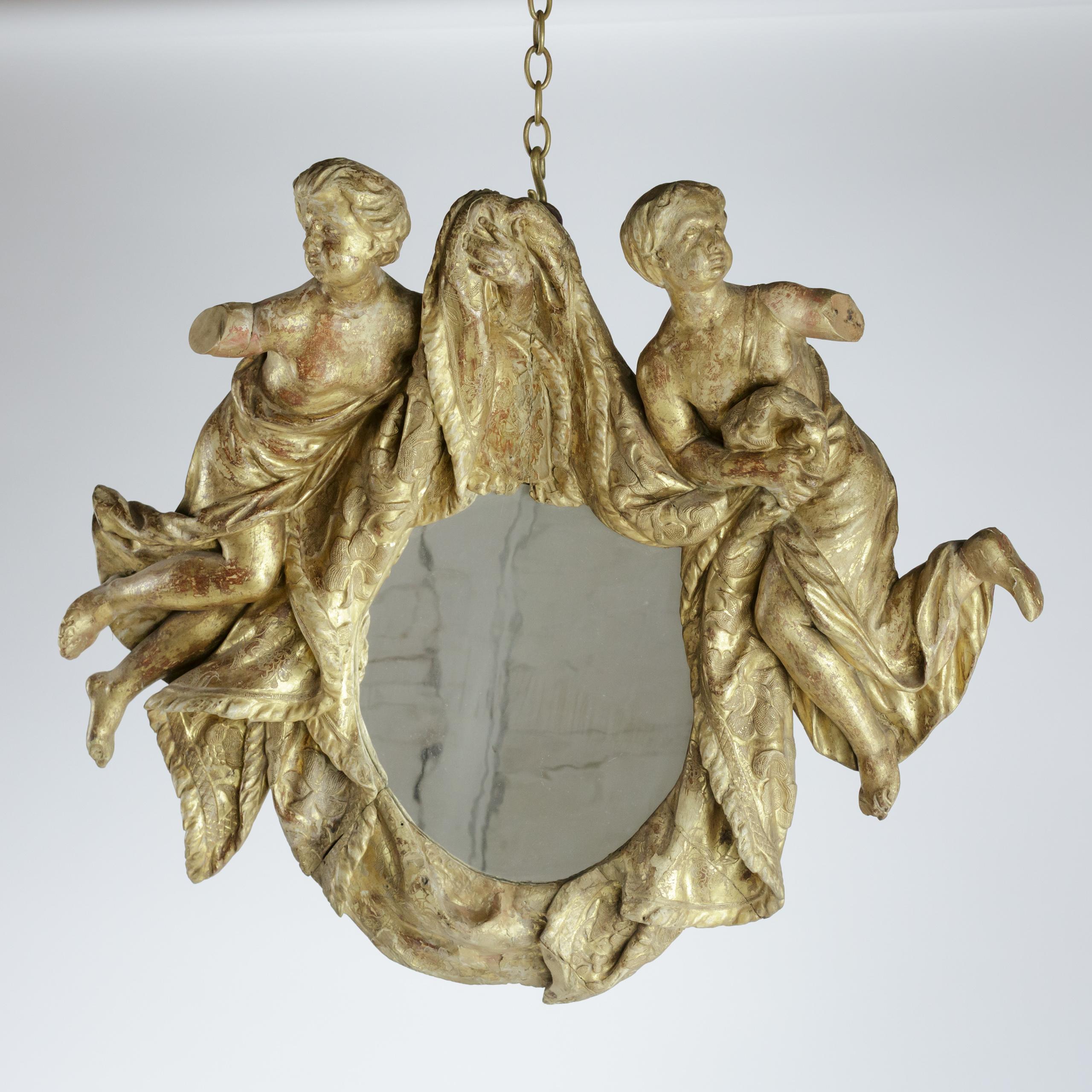 Miroir en bois doré d'époque baroque, un exemple magistral de l'artisanat du début du XVIIIe siècle. Le cadre doré délavé est orné de deux chérubins sculptés de façon complexe qui 