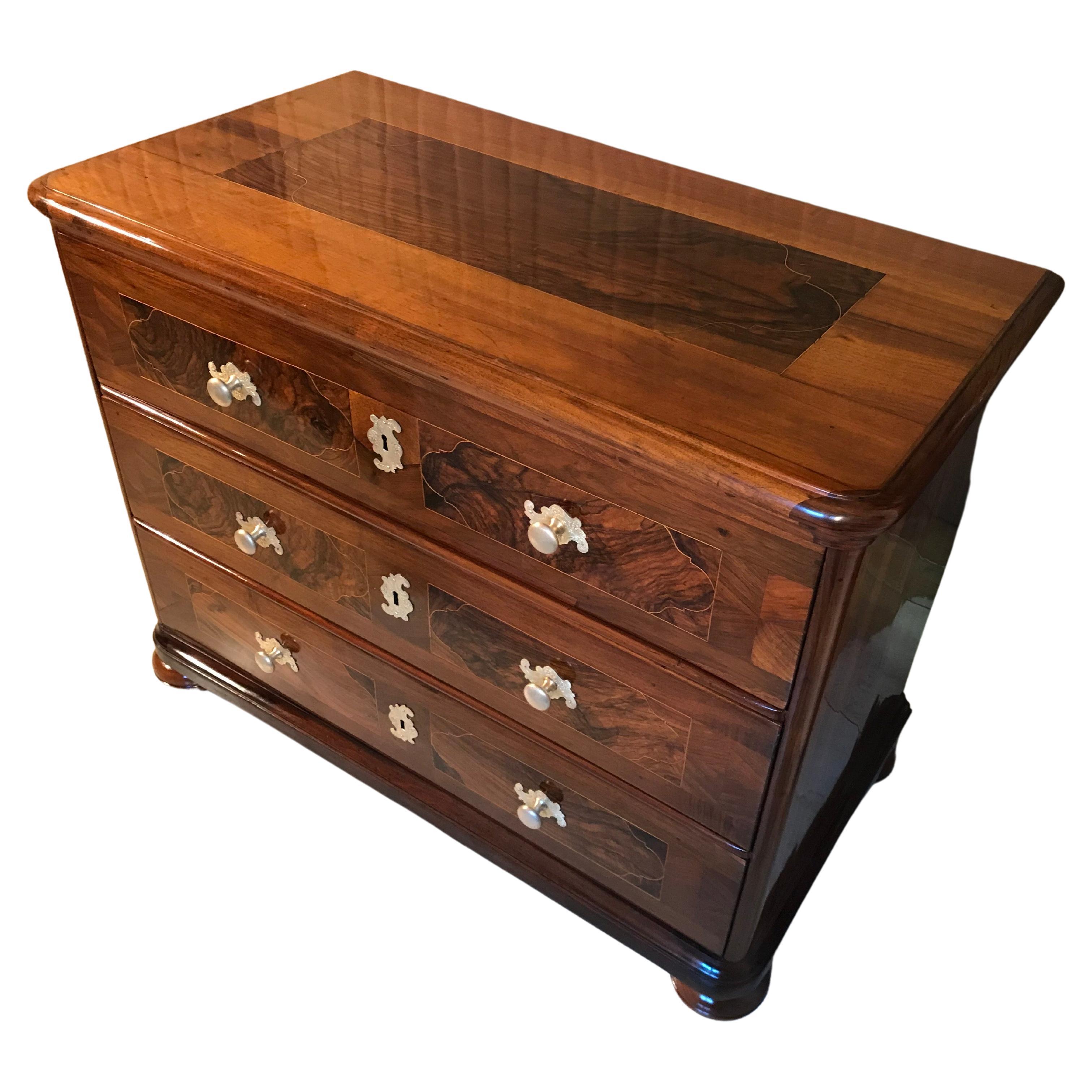 Discover an exquisite 18th-century Baroque chest from Southern Germany. This pretty piece of furniture showcases the timeless beauty of the era. Crafted with precision, the chest features three spacious drawers and is resting elegantly on bun feet.