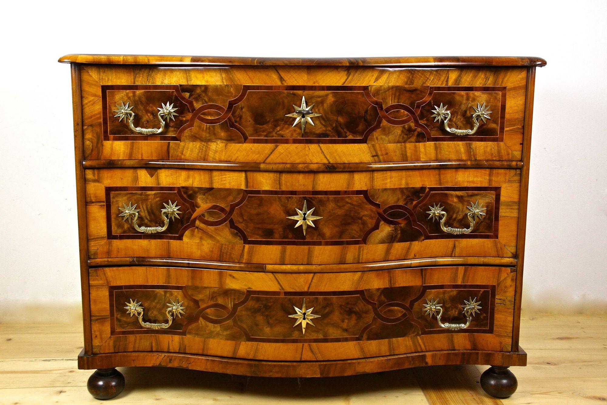 Exceptional baroque chest of drawers from the 18th century in Germany. Elaborately made in the period around 1760, this remarkable baroque commode impresses with outstanding veneered nutwood surfaces and great designed marquetry works. All three