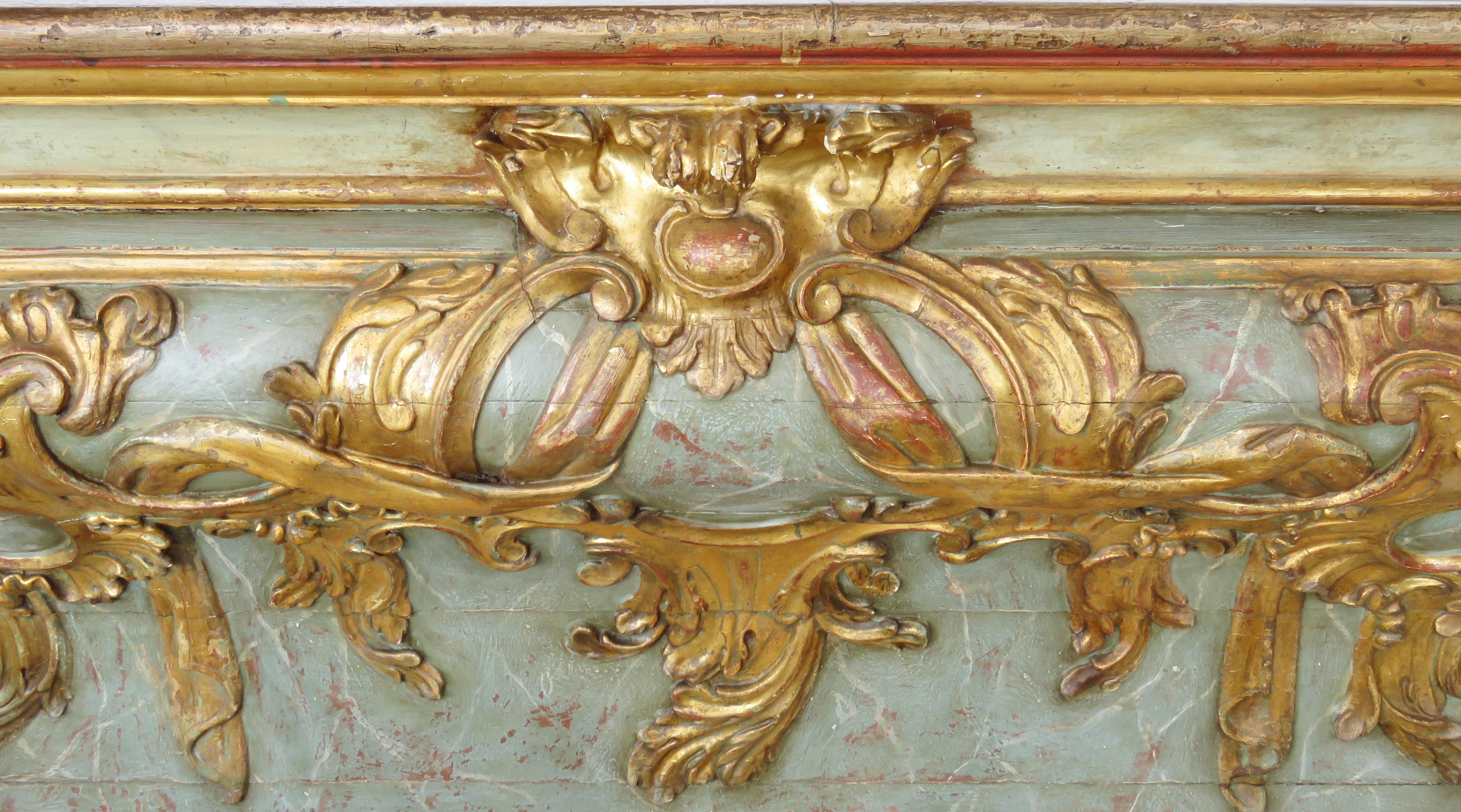 Rectangular molded top over a bombé form case overall paint decorated in faux marble polychrome, exuberant gilt molded foliage and scrolling cartouche on front and sides.

Origin: Leon, Castilla, Spain.