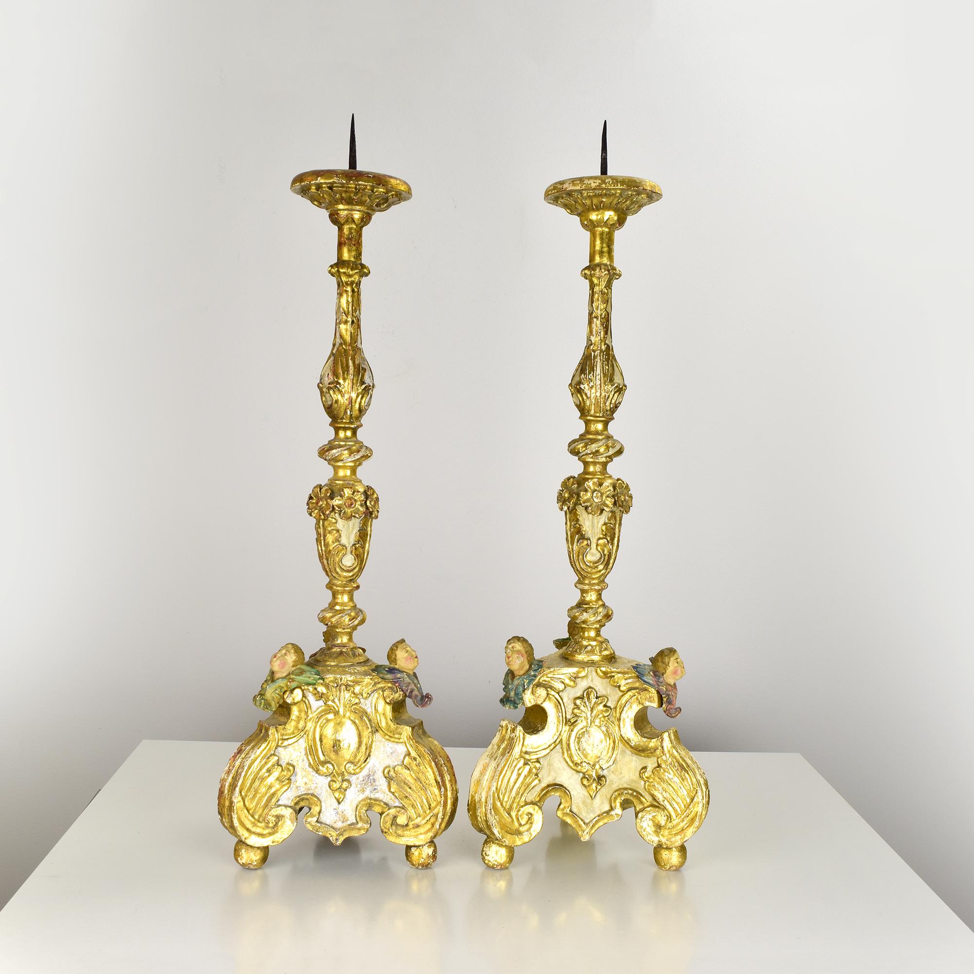 This impressive pair of carved giltwood candleholders dates to the 18th century and was likely created in Southern Europe. Executed in richly detailed Baroque style, each piece features a finely sculpted baluster shaft with floral and foliate