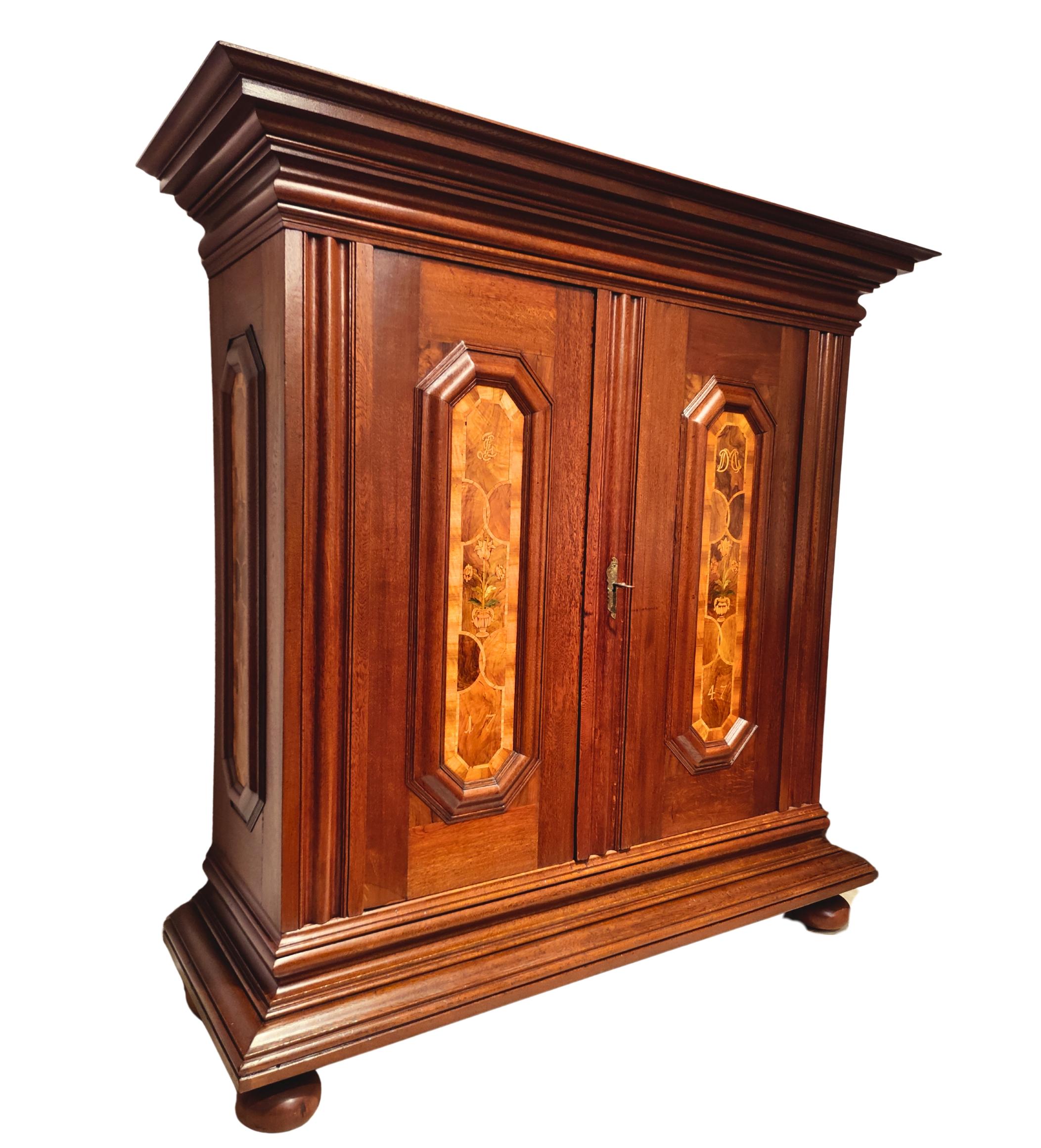 Impressive Baroque wardrobe from Germany, dated 1747. This exceptional cabinet is crafted from solid oak with beautifully contrasting walnut inlays in the door panels, showing subtle geometric and floral motifs. The rich, hand-polished surface