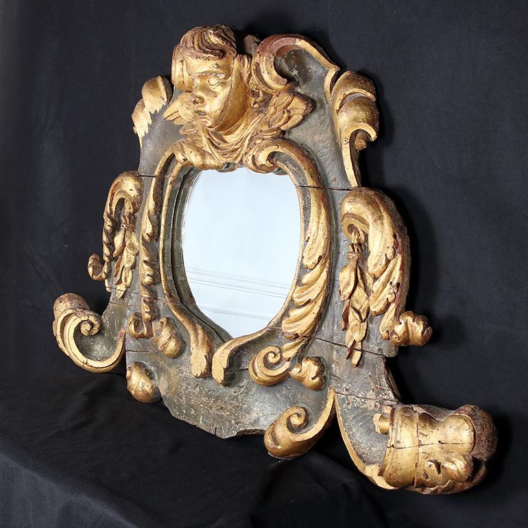 This Stunning and large, giltwood Italian mirror is in the Baroque style. It is highly sculptural with a large cherub at the top with its wings flowing to either side. Robust acanthus leave carvings in large scrolling swirls surround the sides of