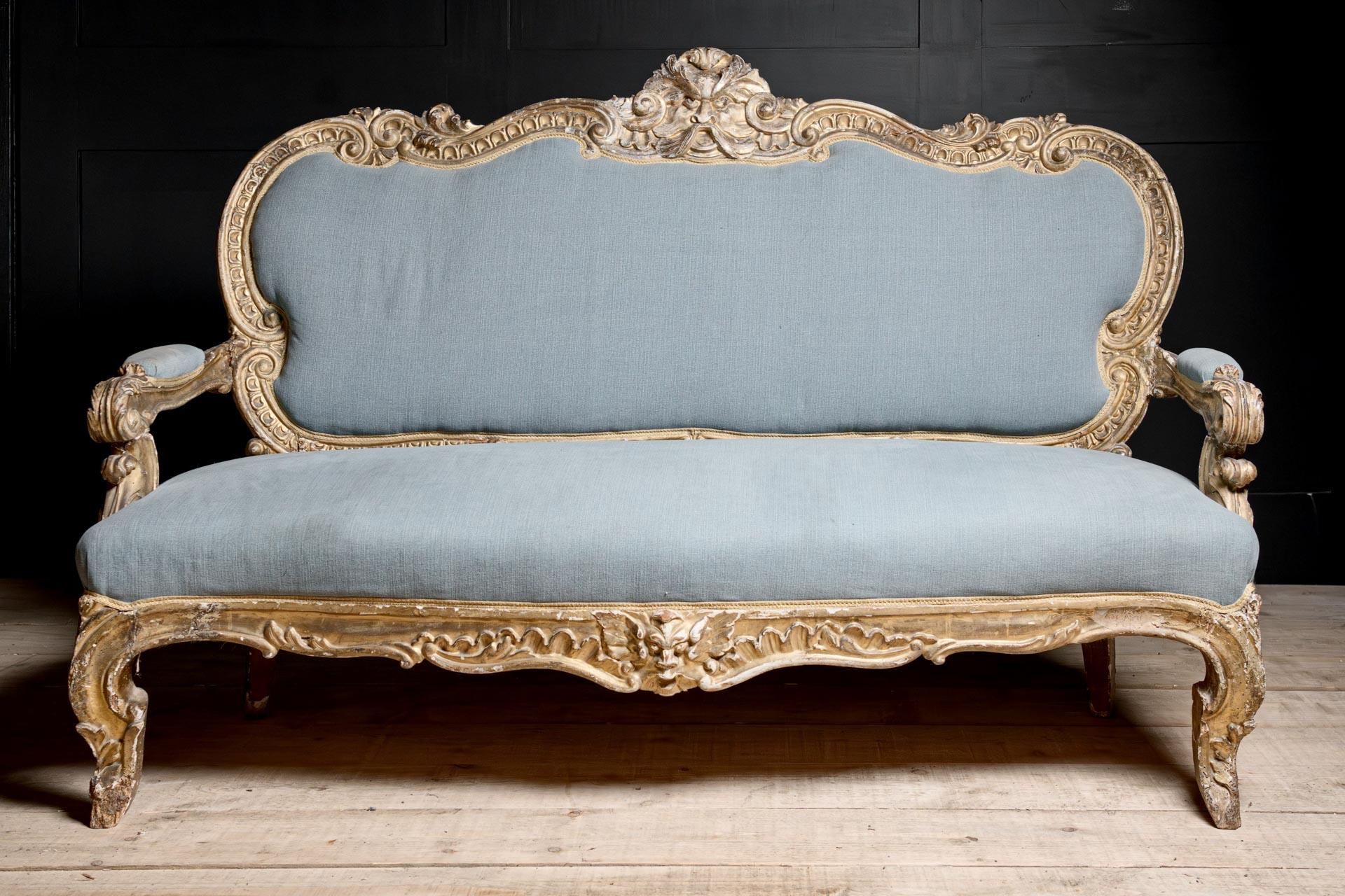 Canapé de salon italien de style baroque provincial du XVIIIe siècle, orné de détails en relief, fini en or pâle doré sur gesso sur bois dur sculpté. Le masque central merveilleusement sculpté d'Éole, dieu grec du vent, orne le dos avec des volutes