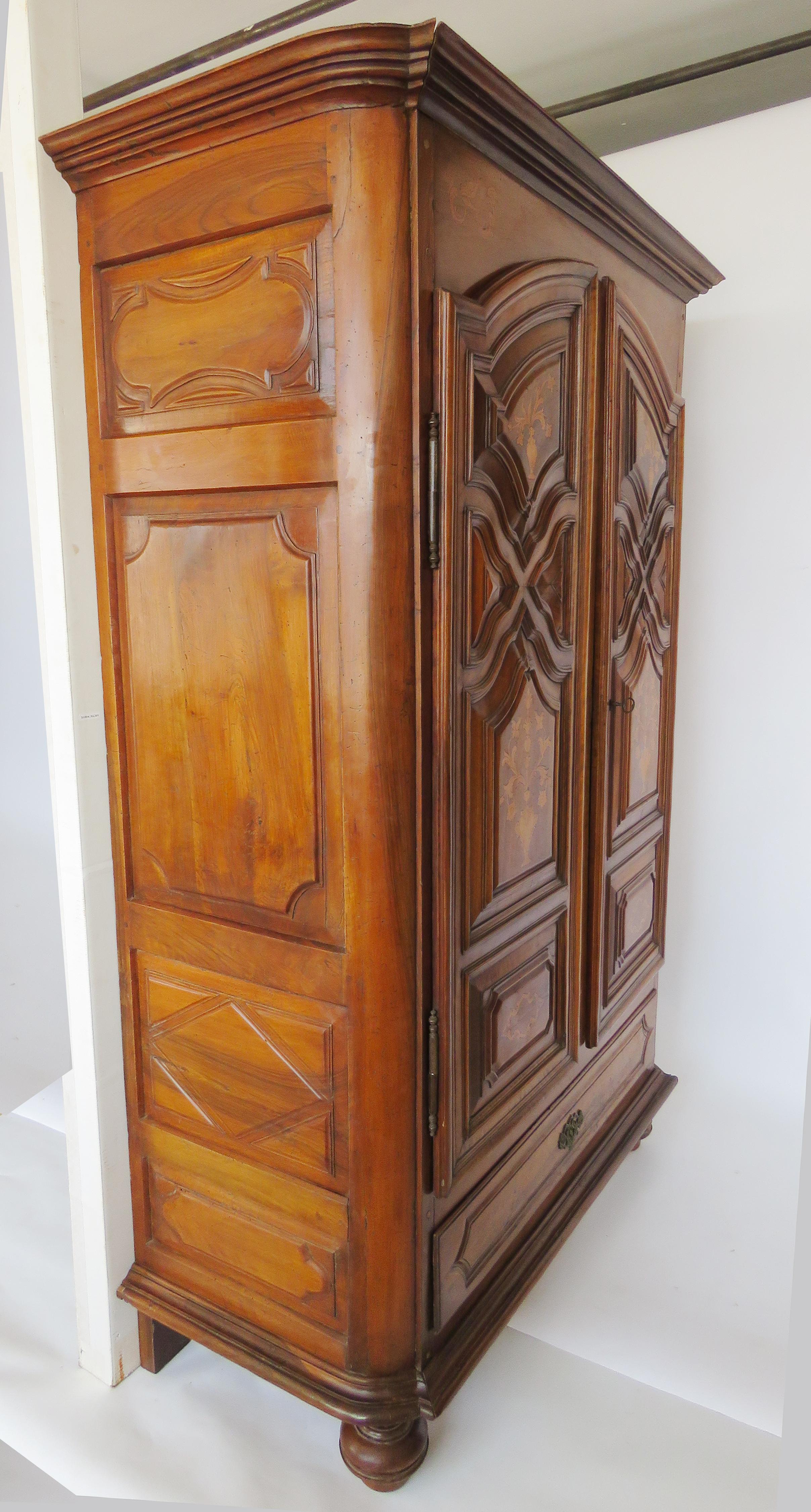 The stepped down curved cornice over two arched elaborately molded paneled doors with inlaid vase and floral designs, over a large lower drawer flanked by paneled sides above molded base raised on turned bun feet.

Origin: Catalonia, Spain.