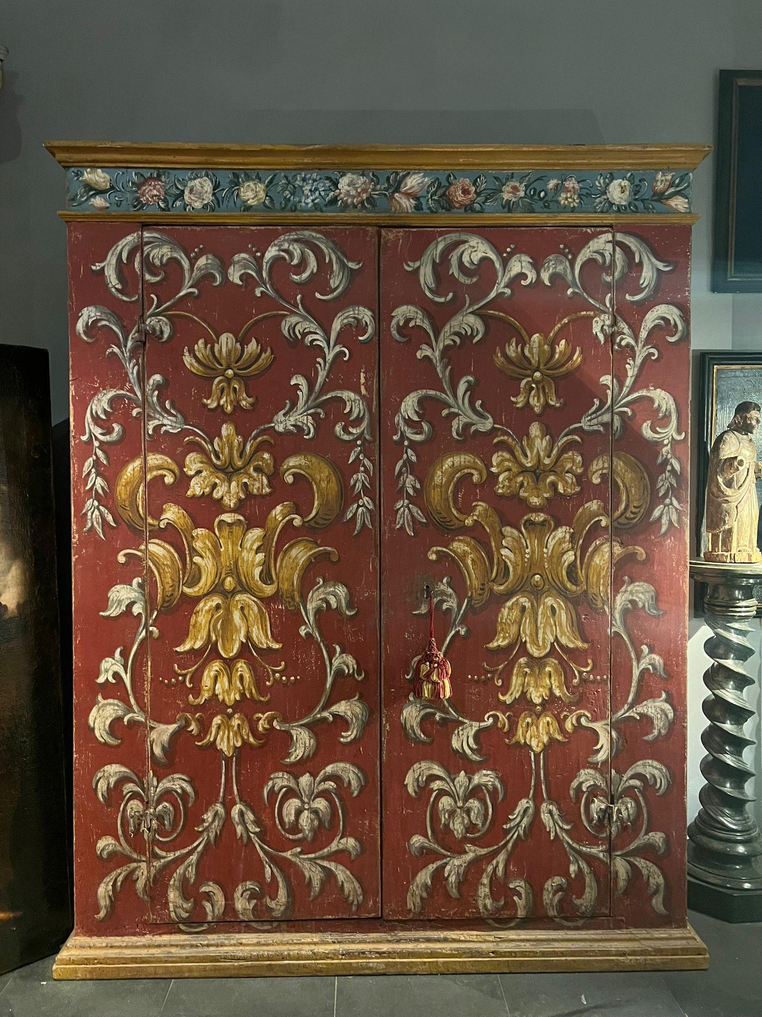 Beau meuble provenant d'un couvent, en bois de peuplier peint.

Les portes de l'armoire sont joliment décorées dans des tons de blanc, de rouge et d'ocre jaune.

La partie intérieure est recouverte de papier journal qui est très particulier et