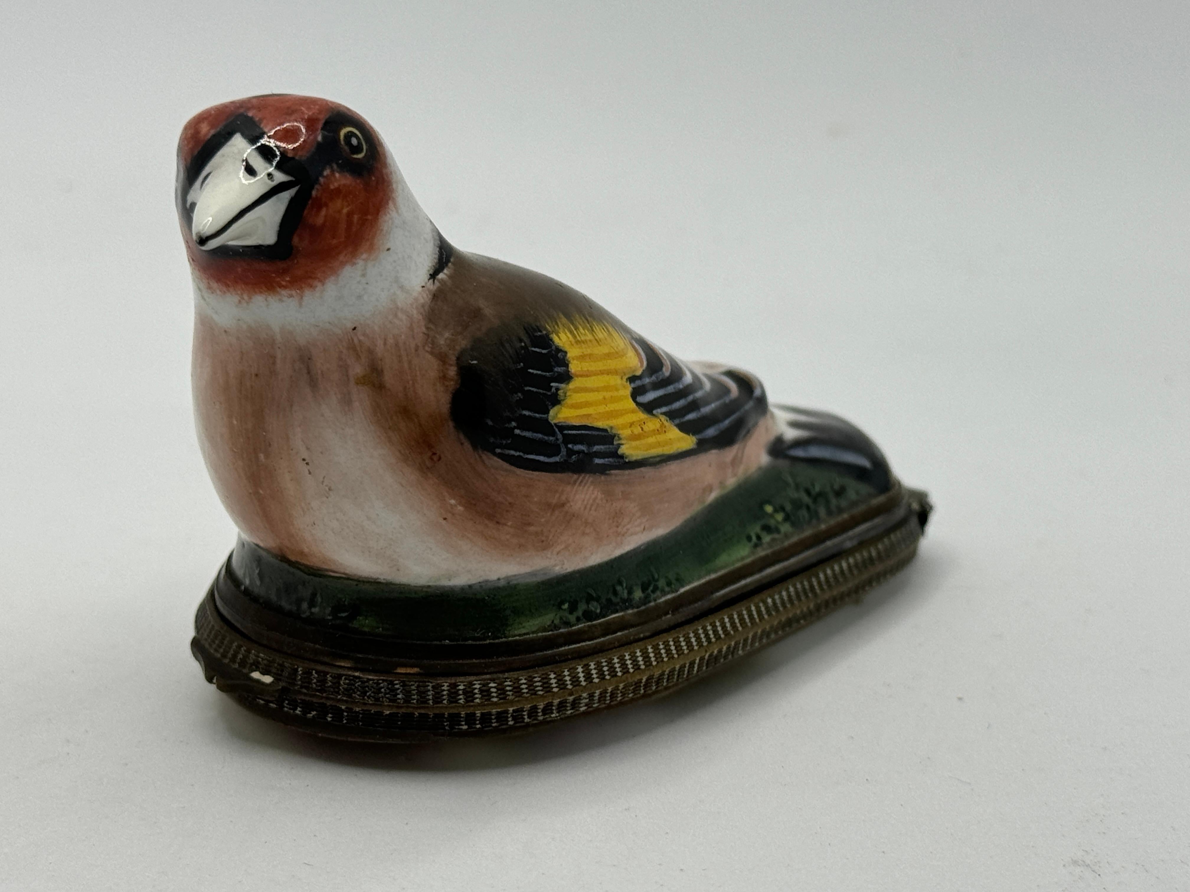 18th Century South Staffordshire Bilston Enamel Bird Patch Box, in the form of a Goldfinch, its eyes outlined with a prominent eyebrow, perched on green base, the lid painted with a bird, castle and children / putti playing, Circa 1760