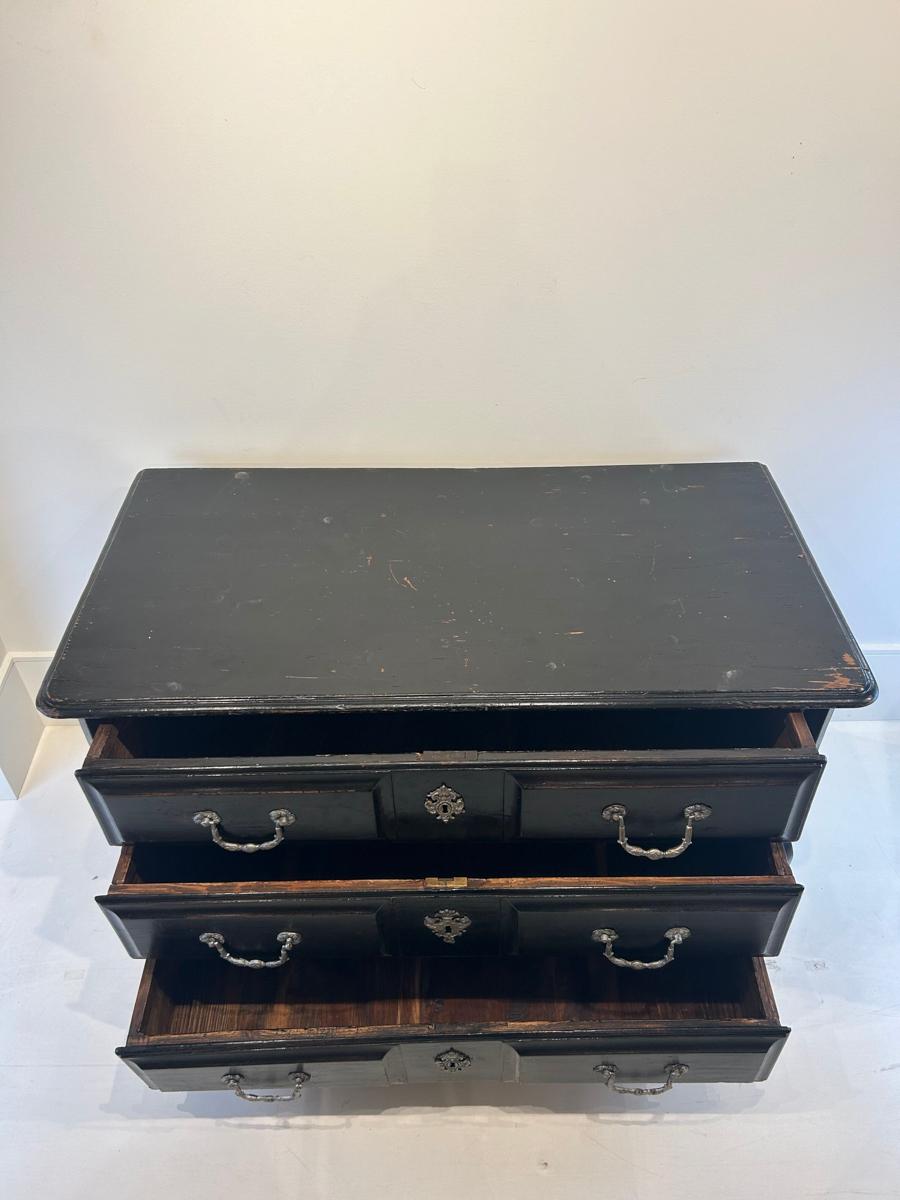 This striking 18th Century black chest exudes sophistication and timeless elegance. The deep black finish of the chest provides a dramatic backdrop for the beautifully ornate silver pulls and keyhole escutcheons, which add a touch of opulence. The