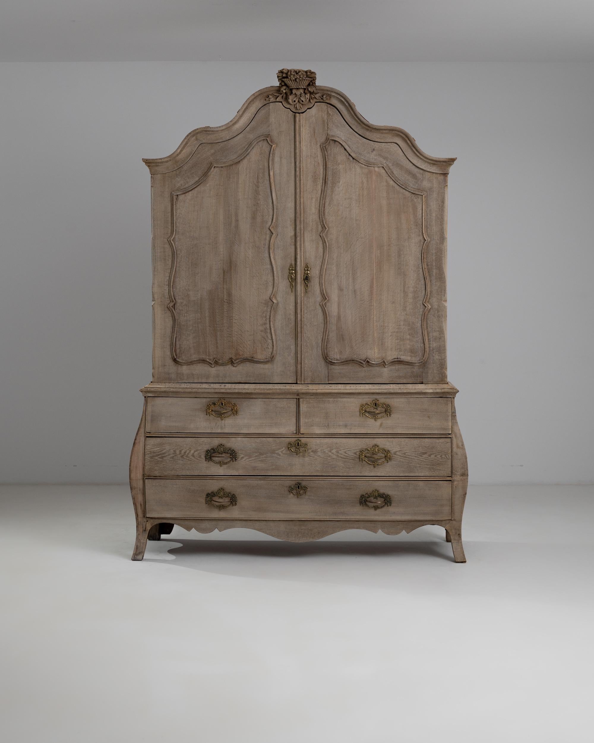 An antique cabinet produced in the Netherlands, circa 1800. This stately chest rests on curving legs, giving its linear form a subtle curve. The curve is echoed in the outline of the panel doors, and crowned by an ornate molding and an ornamental