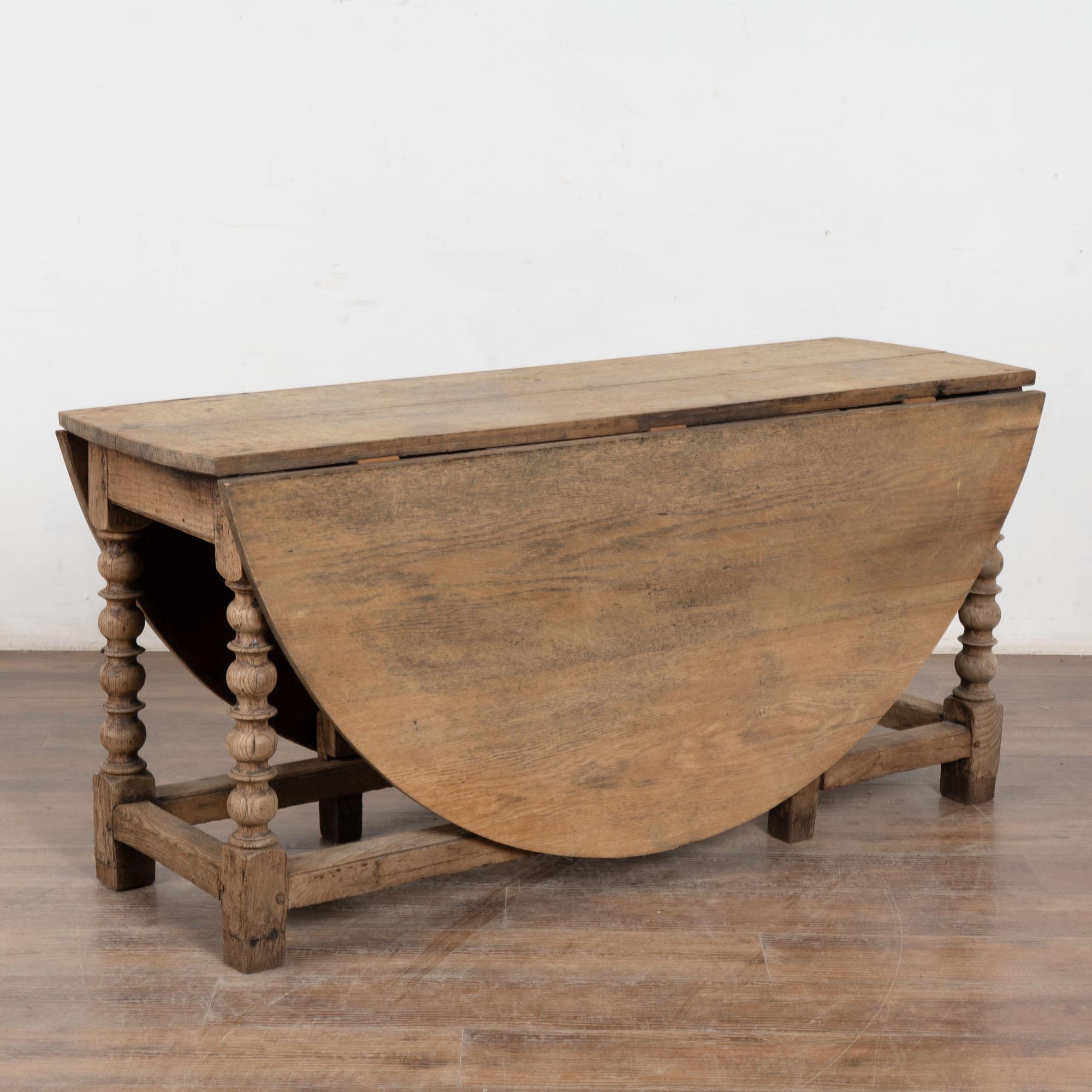 This handsome bleached oak gateleg dining table with decorative turned legs has two drop leaves which allow it to serve as narrow console table as well.
Notice the patina of the oak, aged and naturally distressed over generations of use revealing