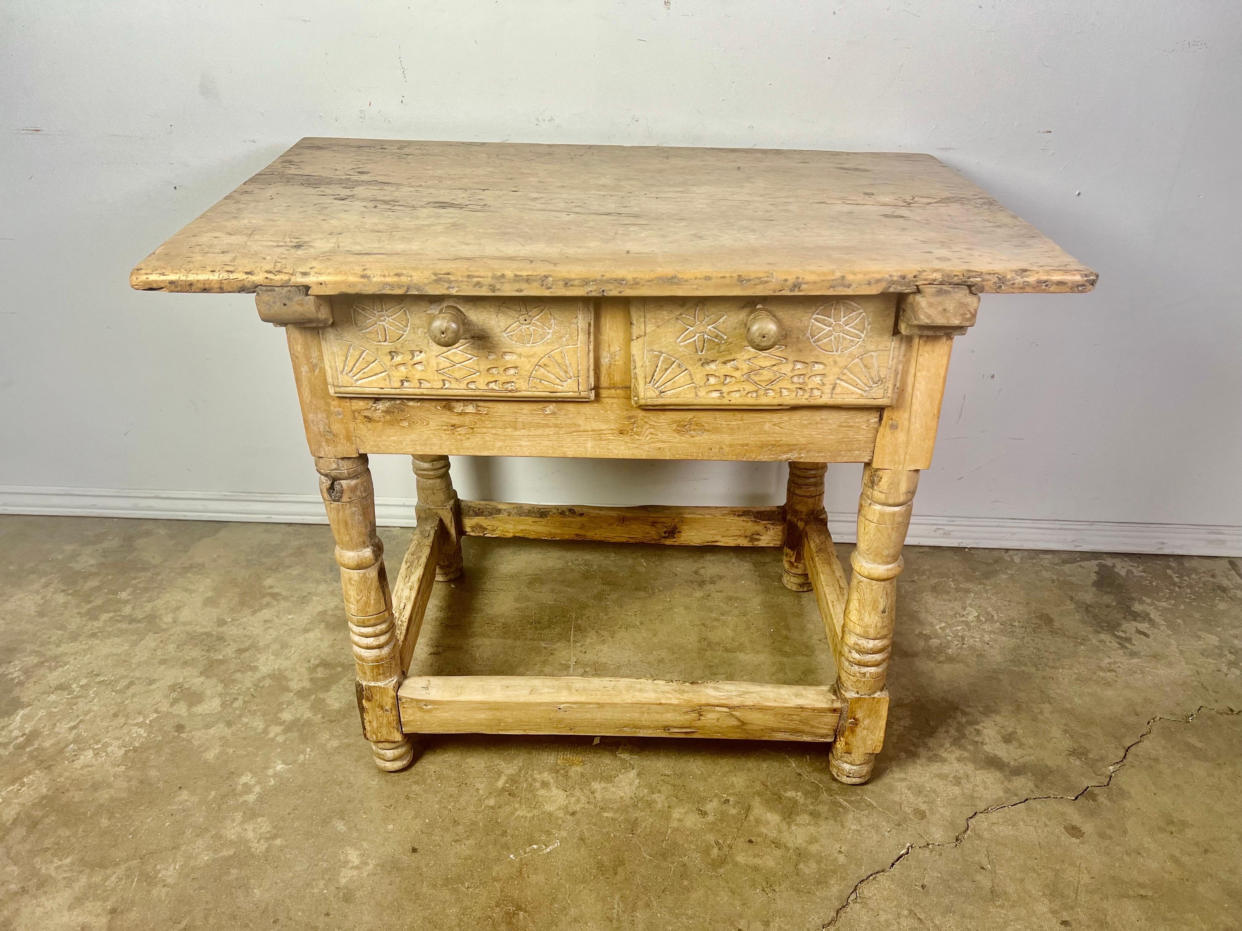 18th century bleached walnut Spanish Colonial table with two drawers. The four legs are connected by a stretcher. The two drawers have primitive style carvings.
It is beautifully worn and has a nice patina.