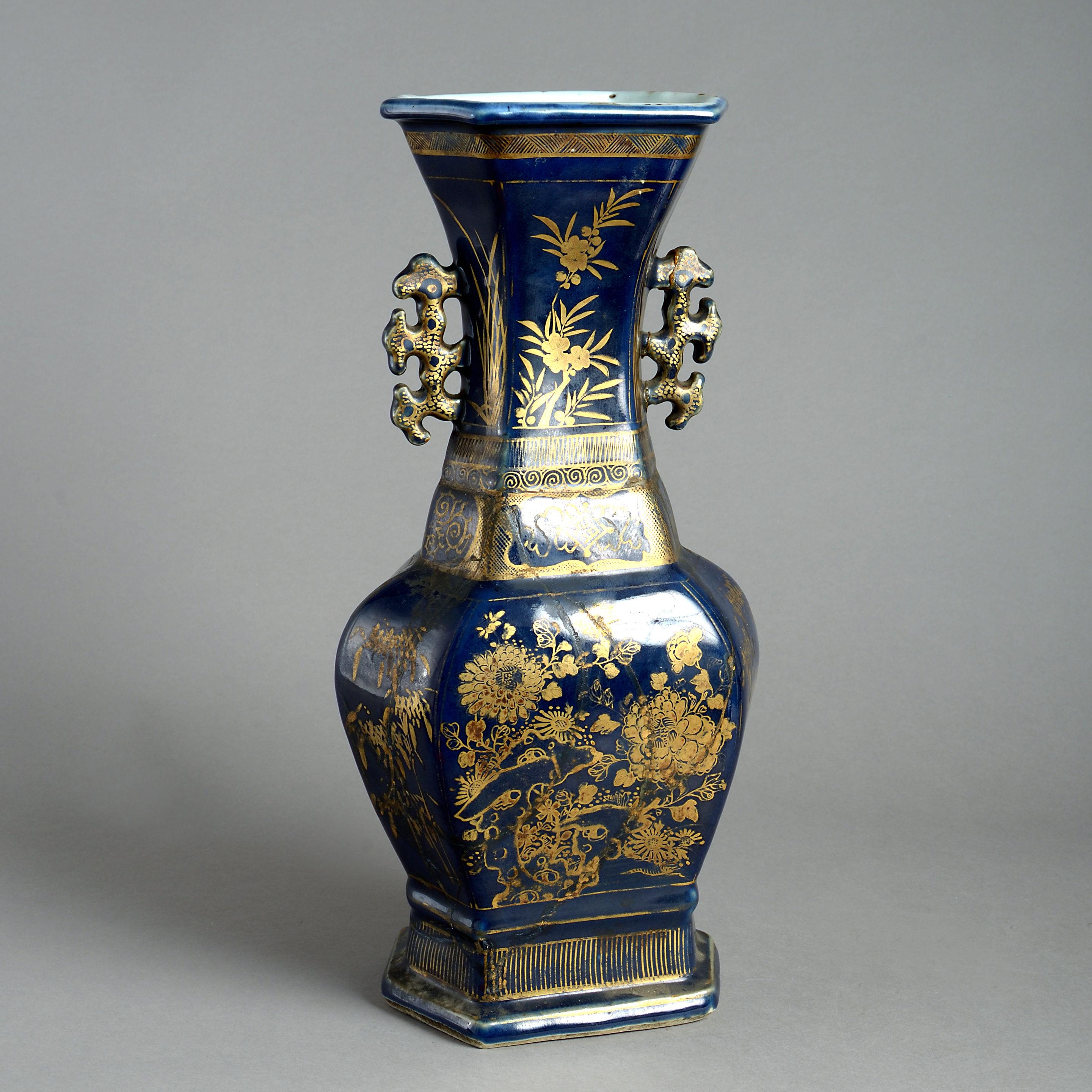A late 18th century porcelain vase of faceted form, having handles and gilded decoration throughout upon a deep blue ground. 

Restored throughout.