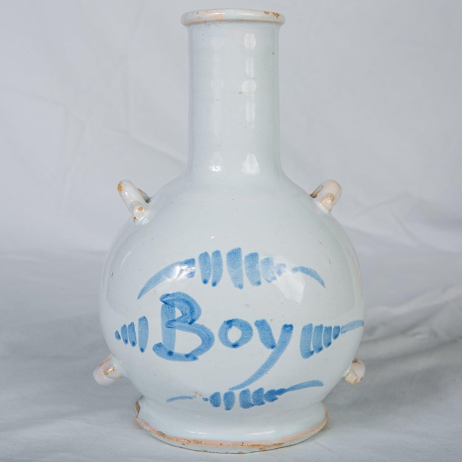 Cette bouteille en Delftware anglais bleu et blanc, fabriquée vers 1750-1760, a un col haut et étroit avec un bord légèrement évasé sur un corps globulaire distinctif. La décoration est le mot 