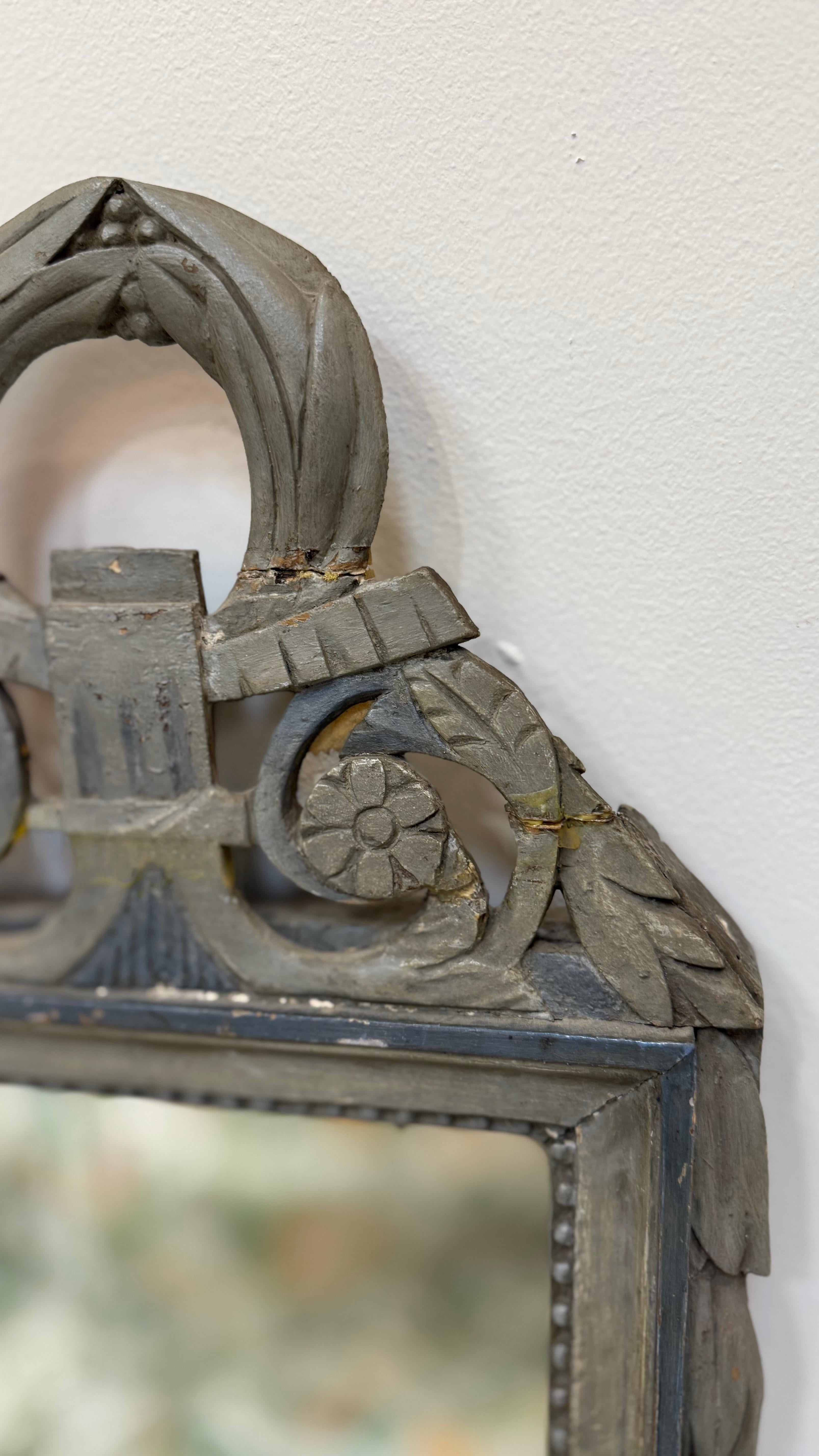 Charmant miroir de mariage parisien du XVIIIe siècle, délicieusement sculpté et peint à la main dans des tons de bleu et de blanc délavés. Le cadre est orné de délicates feuilles de laurier, de détails perlés et d'une paire de rosettes stylisées