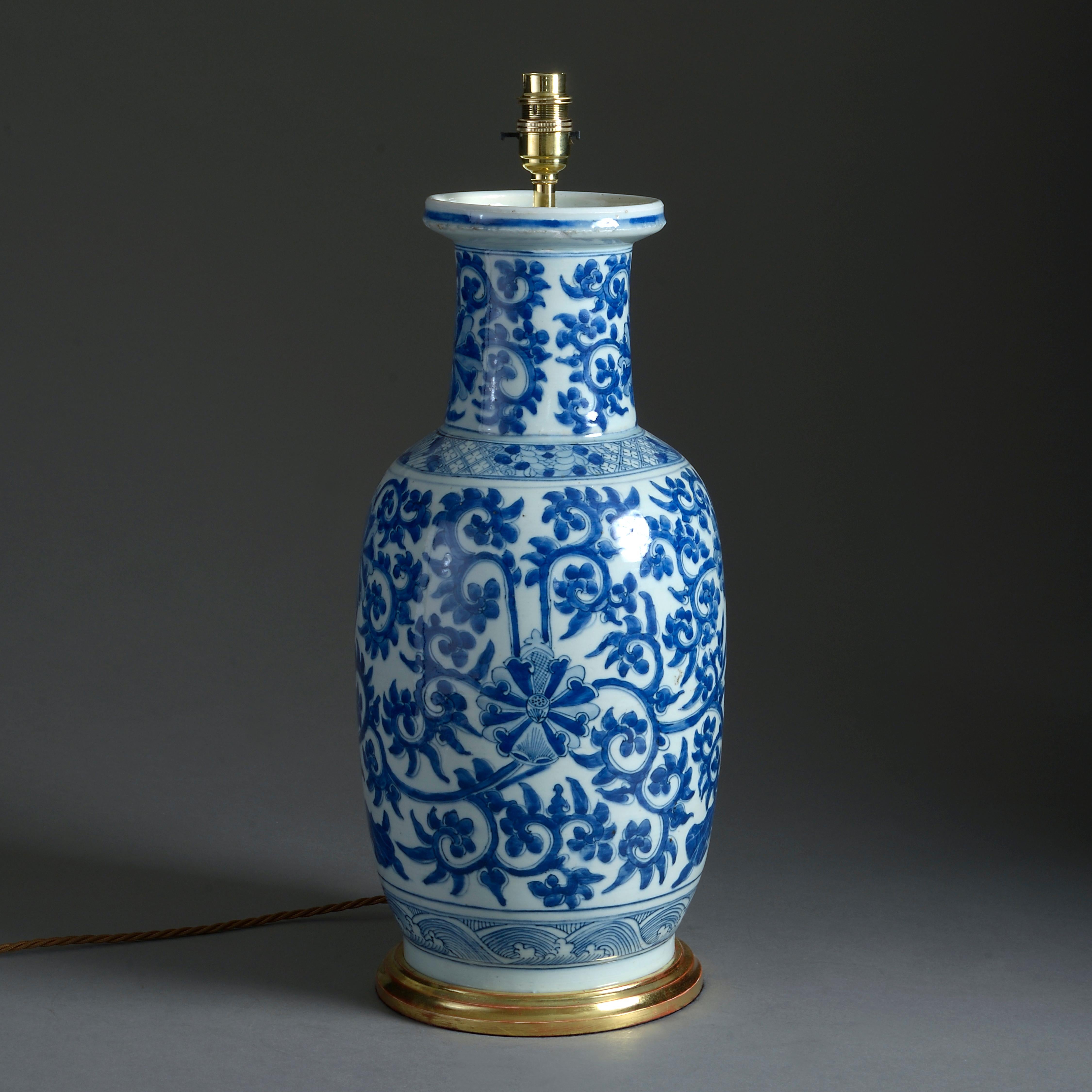 A mid-18th century porcelain vase of good scale, the neck and body decorated with scrolling foliage in blue glazes upon a white ground. Now mounted upon a turned giltwood base as a lamp.

The vase, Chinese Export, Qianlong Period