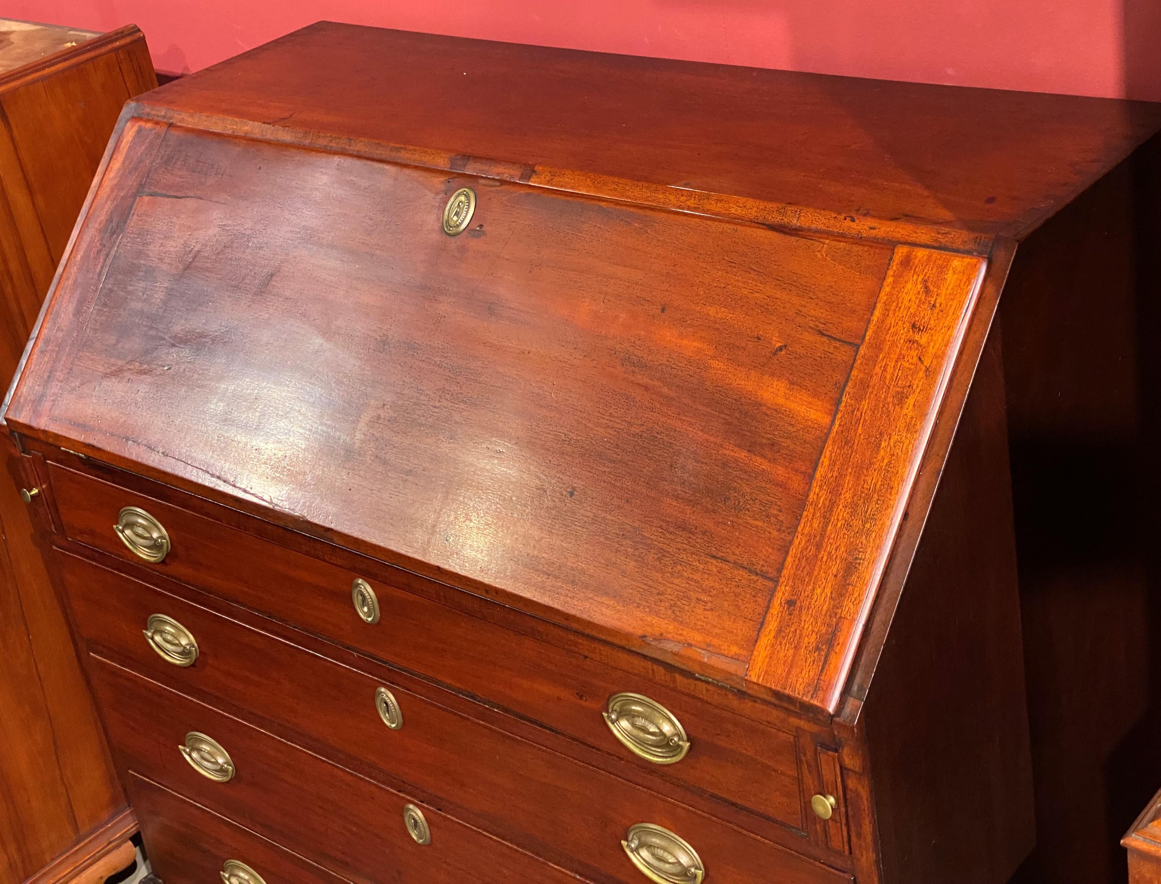 A good example of a Chippendale mahogany slant front desk with compartmentalized interior, including valanced cubbies and fitted drawers, over four graduated dovetailed drawers with oval replaced period brasses, all supported by nicely carved ball &