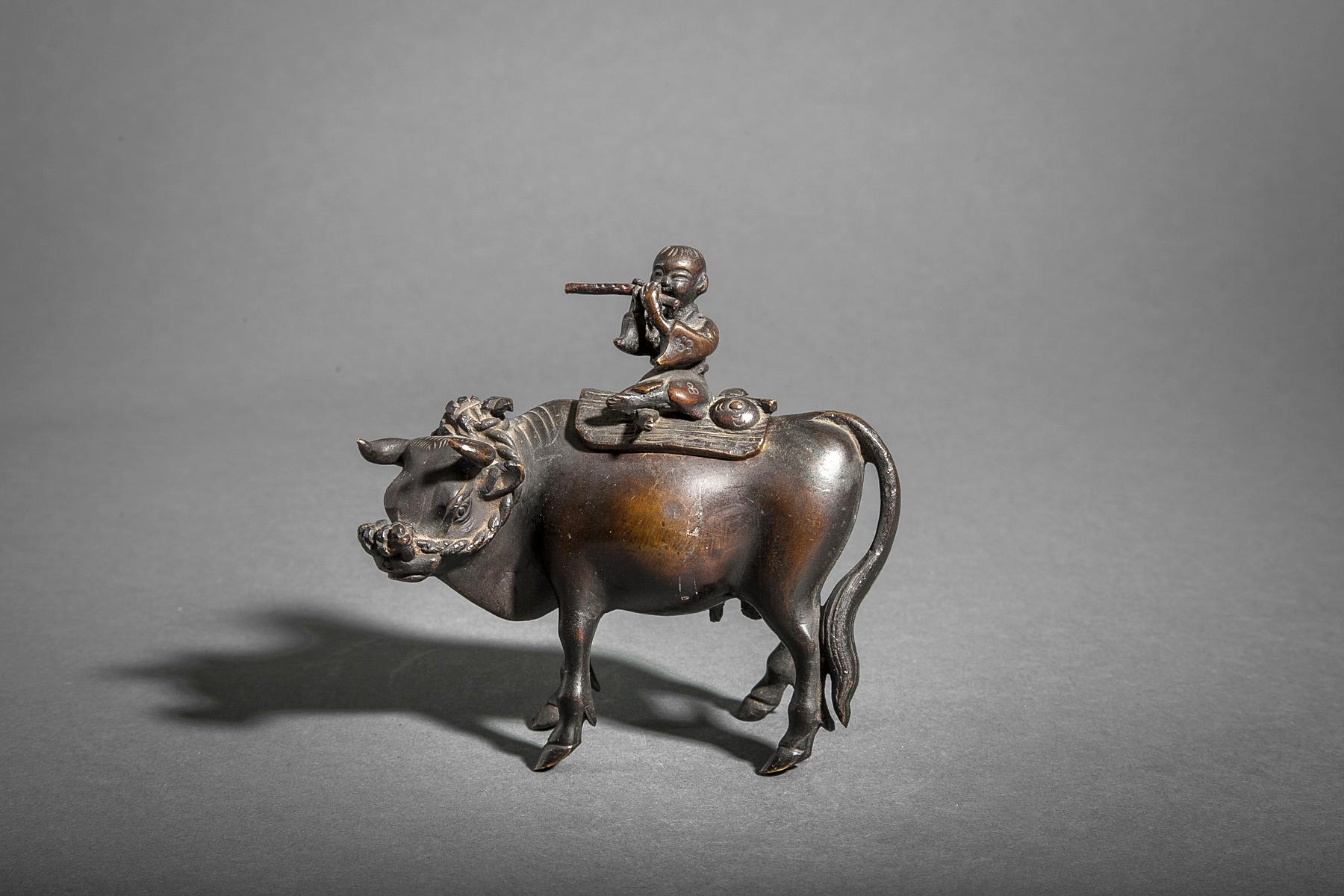 An incense burner in the shape of a boy playing a flute while riding a bull. The boy is the removable top to the incense receptacle located inside the bull's body.