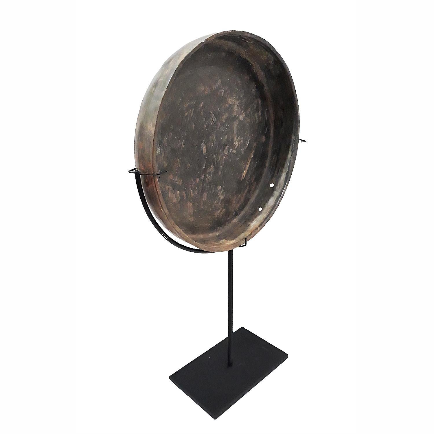 A bronze mirror or tray from Thailand, early 18th century. Mounted on a black metal stand. 

Traditionally used with water or oil to enhance reflection when used as a mirror, it now has a natural patina conferred by the action of time and the