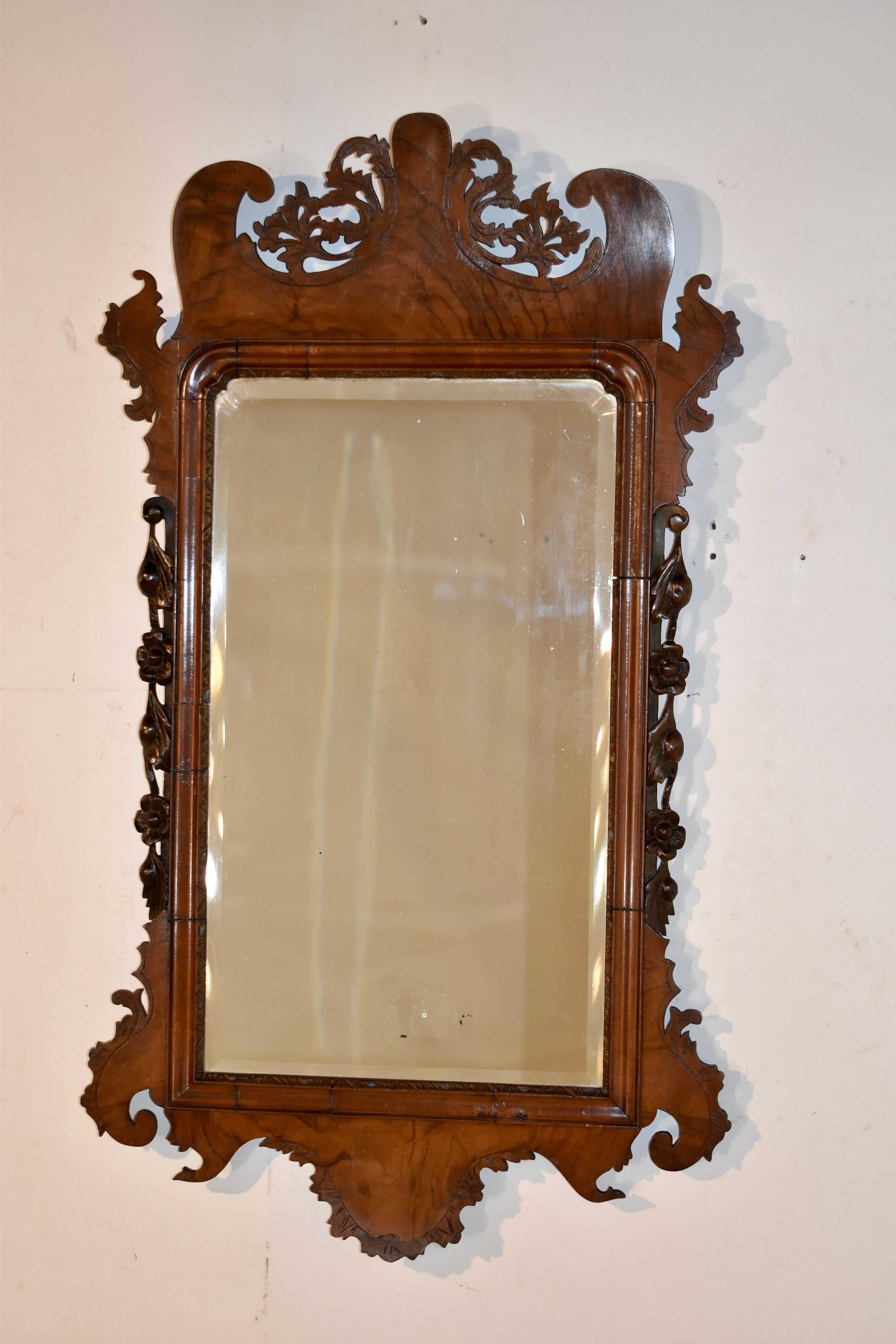 Magnifique miroir mural Chippendale du 18e siècle en ronce de noyer.  Le cadre est spectaculairement sculpté à la main dans des motifs ornementaux avec des fleurs qui descendent le long des côtés du cadre du miroir.  Le miroir est placé dans un