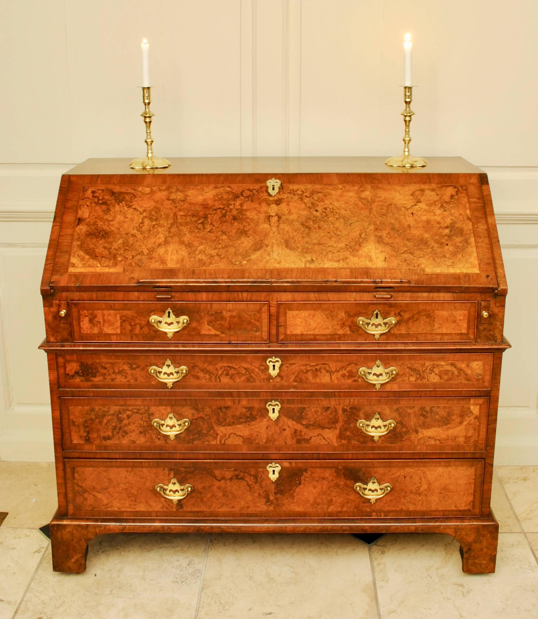 A handsome example of a burr walnut bureau with herringbone bandings and cross grain waist mouldings retaining the fine original set of brass handles. Standing on the original bracket feet with castors and with carrying handles to the side. Superb