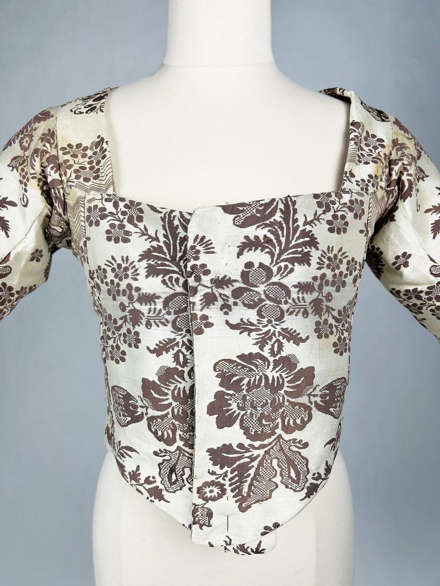 Circa 1780
Francia
Caraco in taffetà di seta broccato risalente al periodo francese Luigi XVI. Taglio curvo con due lati incrociati da appuntare sul davanti, maniche a tre quarti piegate e taglio 