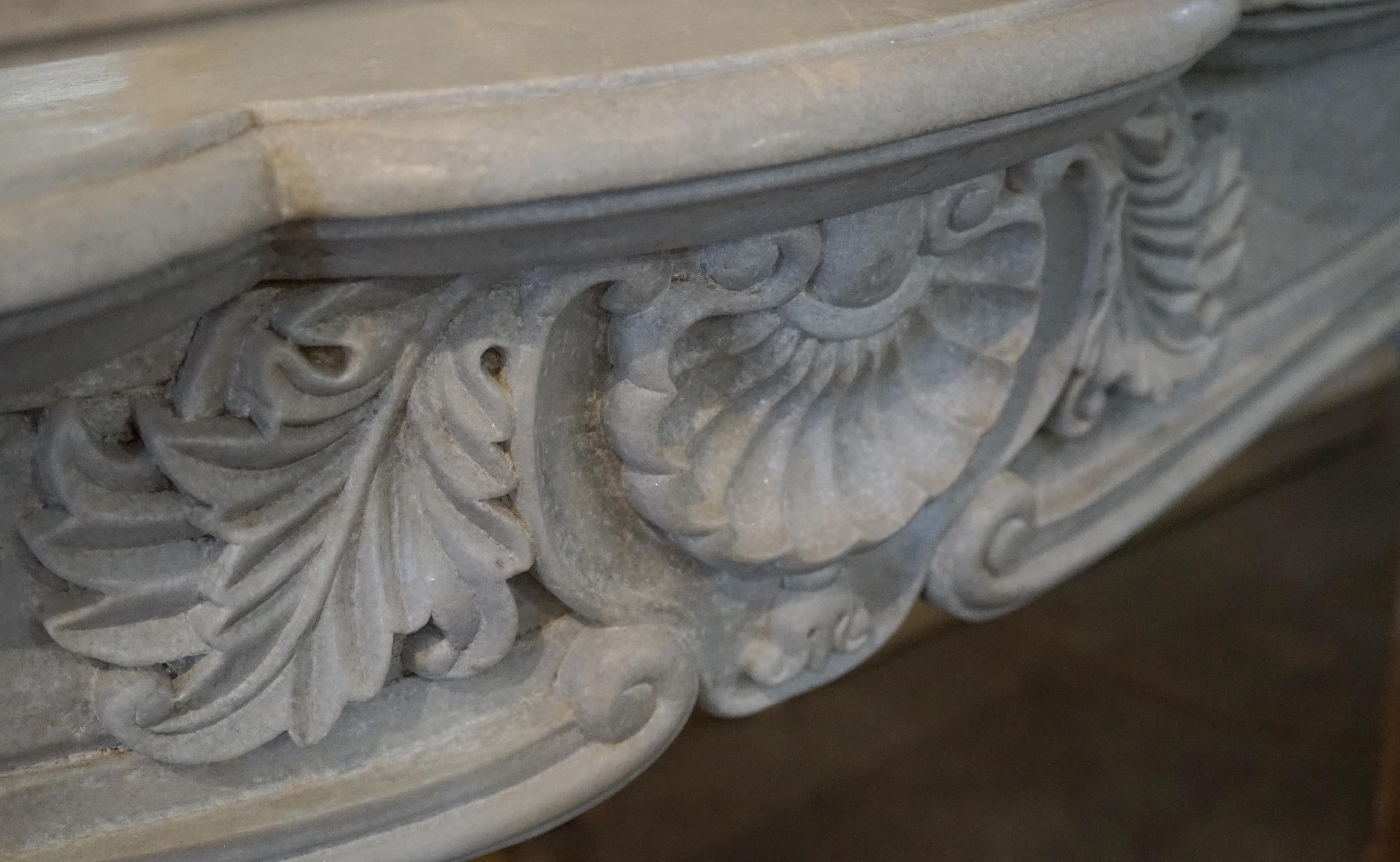 A fine 18th century Carrara marble mantelpiece
Carved in the Rococo style of a dove grey marble, this tall and leggy mantel has an elegant form with a shallow profile. The deeply carved entablature features a central design of leaves, shell and