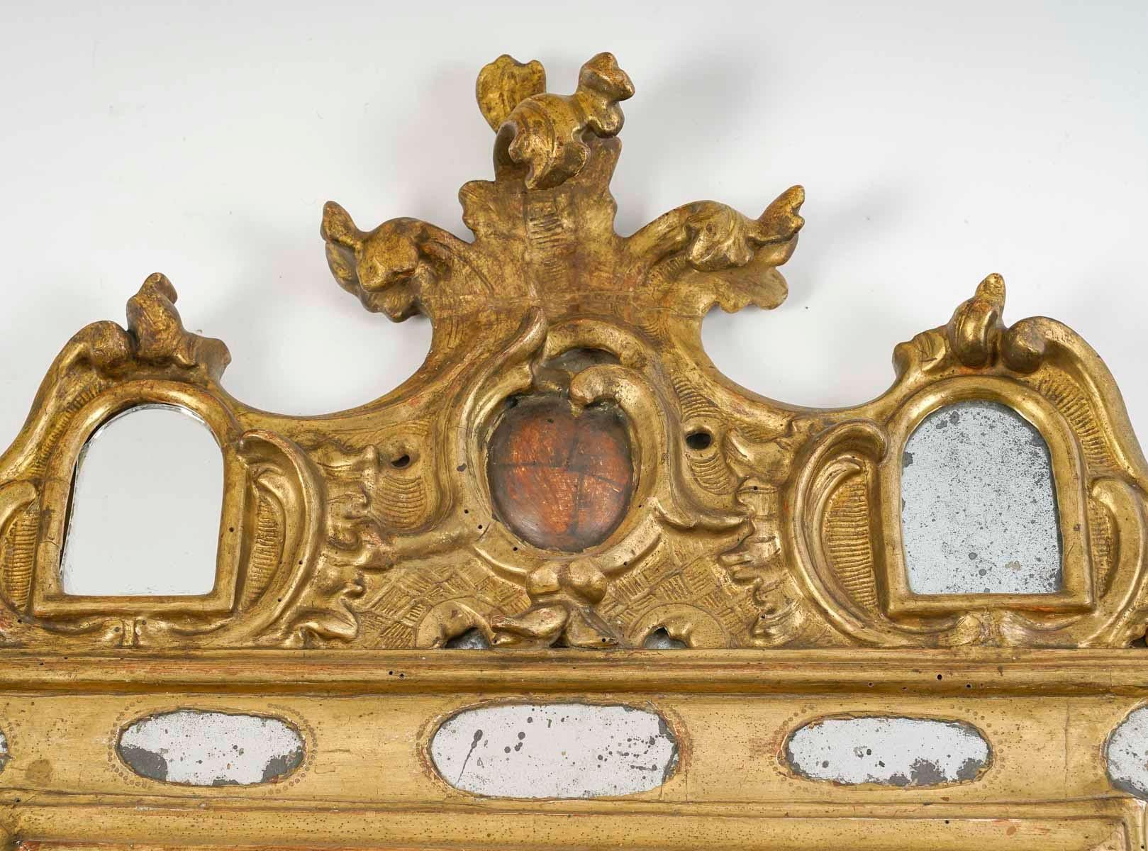 Miroir en bois sculpté et doré du XVIIIe siècle.

Miroir en bois sculpté et doré du XVIIIe siècle avec perles de verre, travail d'Amérique latine ou d'Espagne, ( 2 petits miroirs fendus ).
h : 98cm, w : 71cm, d : 5cm