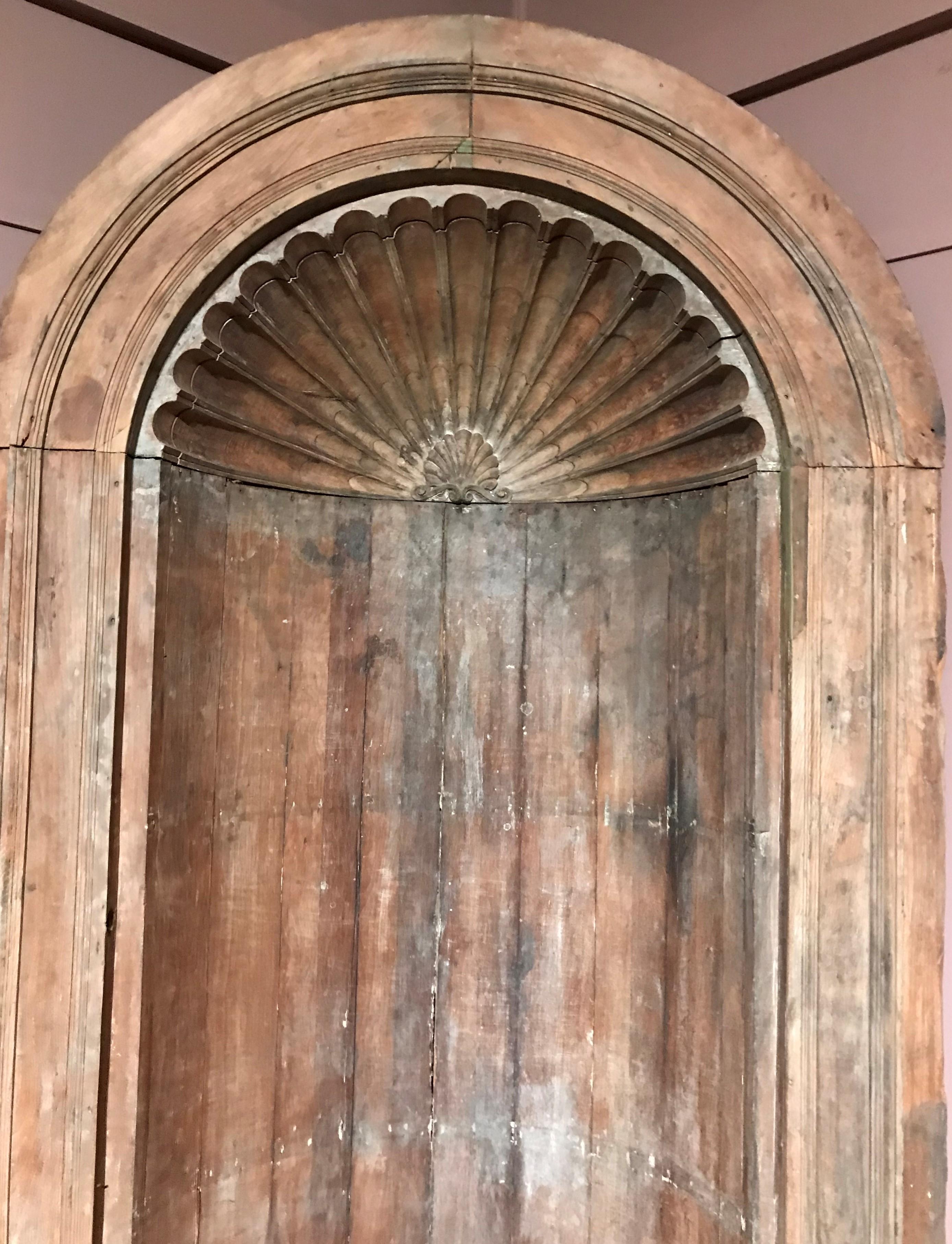 A fine one-piece built-in architectural corner cupboard with arched top and back , featuring scalloped shell decoration and a continuous molded surround, with a single shaped shelf and paneled base. Dates to the 18th century in very good condition