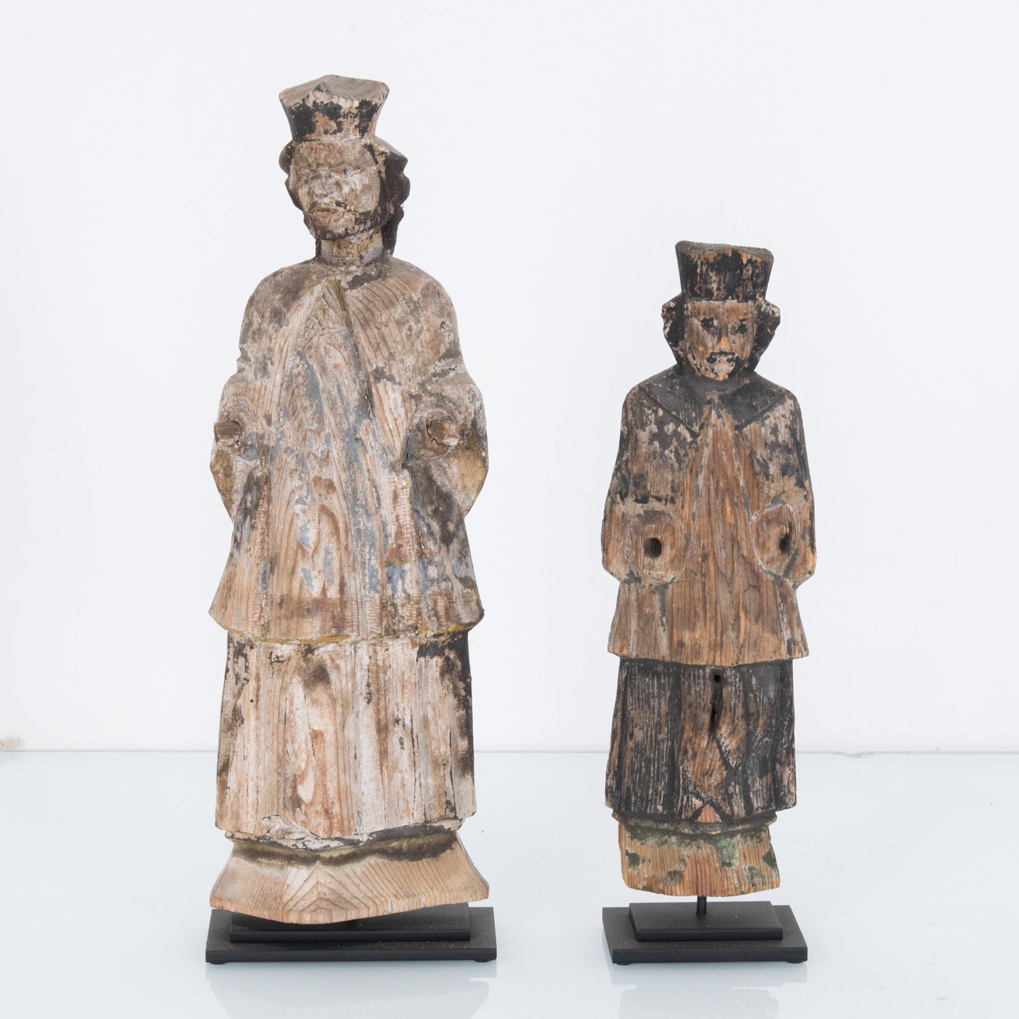 A pair of carved wooden figures from Central Europe, circa 1780. Once painted, the stripped back finish of the natural wood reveals a fluid, expressive grain. Flowing robes and small hats suggest that these figures belong to nobility or priesthood.