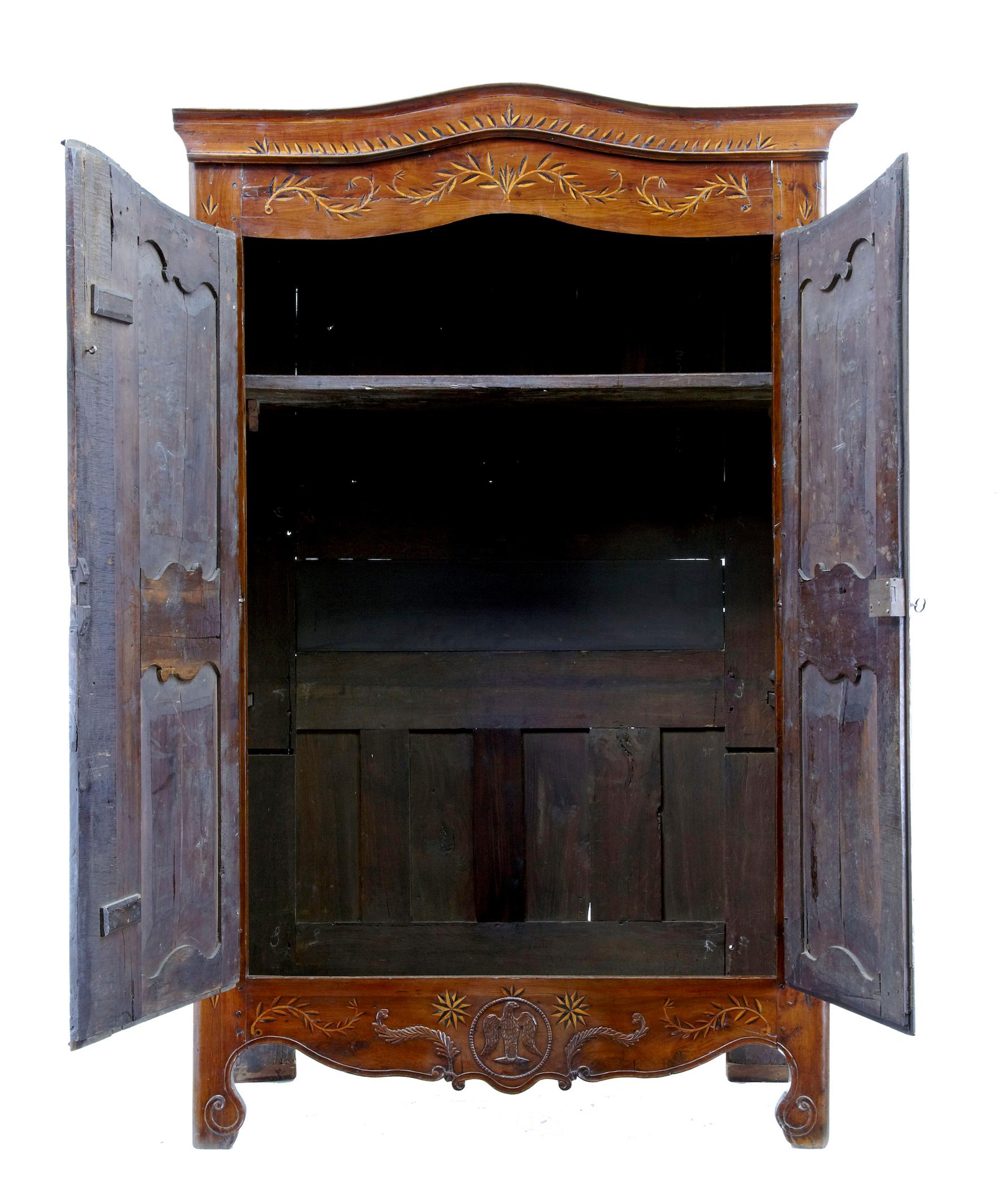 This sort of armoire is also known as a marriage armoire.

Cornice and front are profusely inlaid with a leaf design, with a snake flowing up the middle of the doors, with pierced metal escutheon plate. Rare addition to this piece is a carved