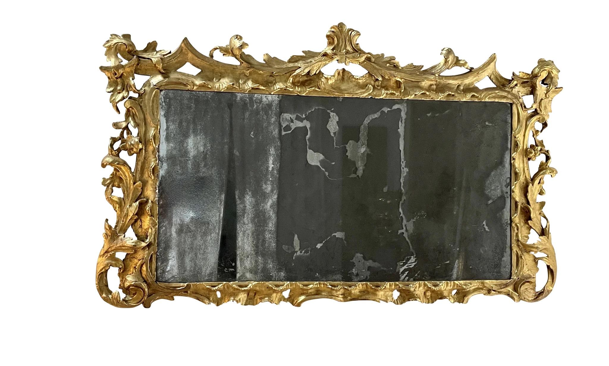 Italian Eighteenth Century ornately carved wooden mirror, with gilded surface, ornate floral and acanthus leaf design, having an early mirror plate.,19 1/2