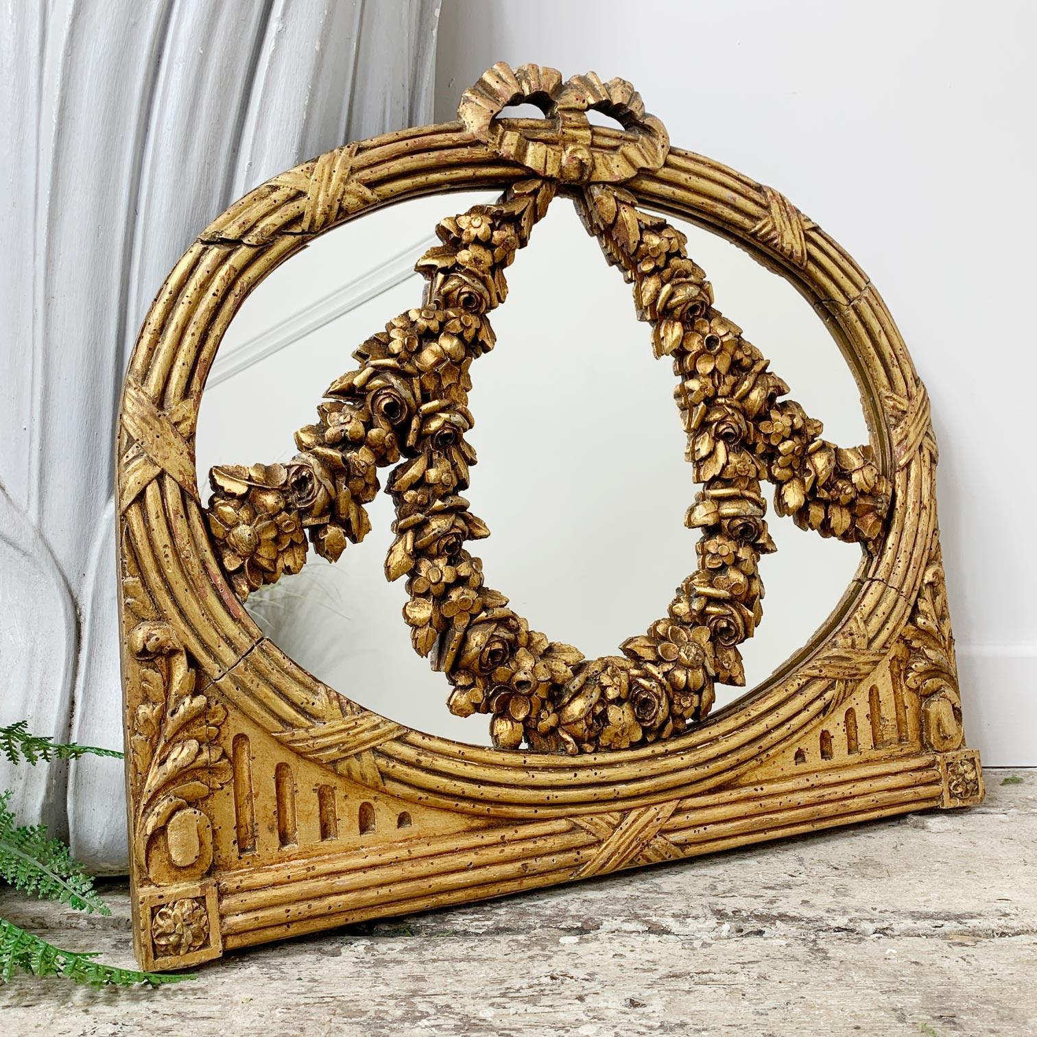Beautiful and charming later 18th century mirror, the frame in carved gilt wood, with very unusual and intricately carved floral swags to the front that sweep across the mirror face.

The glass mirror plate is a modern replacement, the frame does