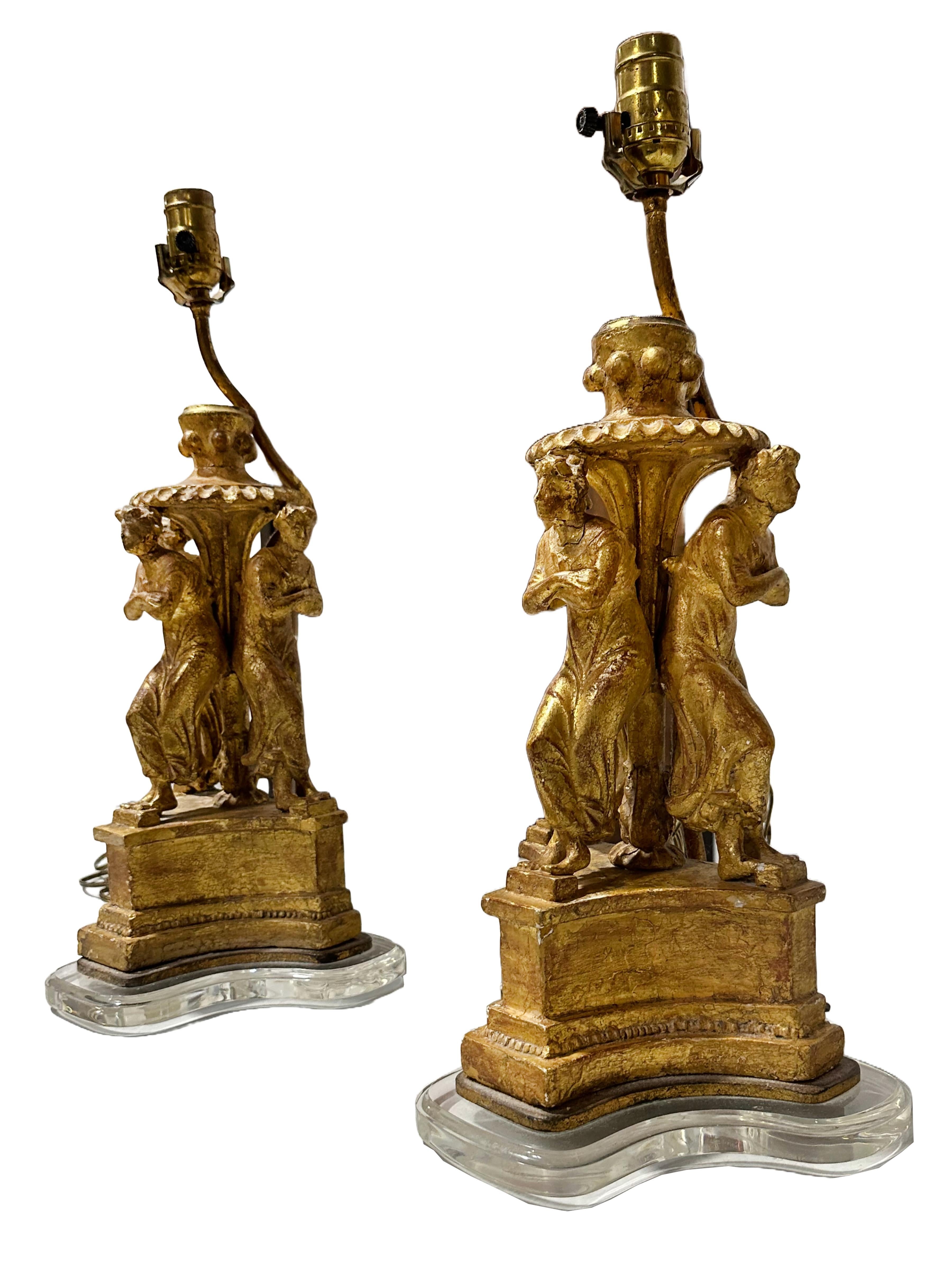 Une belle paire de lampes en bois sculpté et doré représentant la danse des muses. Comprend trois femmes postant sur différents côtés de la pièce. Ensemble de sculptures du 18e siècle  fragments transformés en lampes sans appartenir aux sculptures.