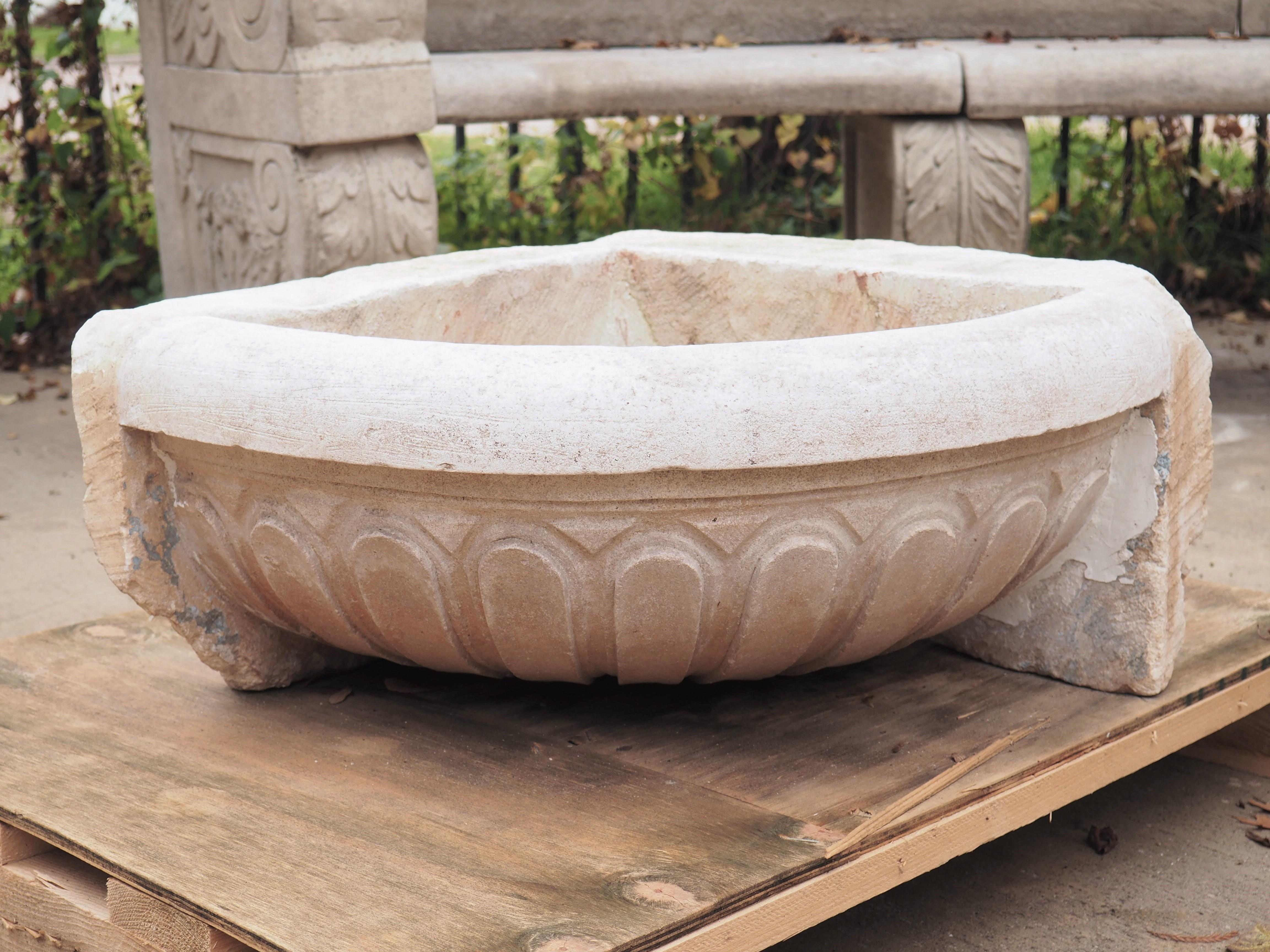 This stone piece was once the basin for a corner fountain or used as corner sink on a property in the rugged hills of Provence, France. It features a thick quarter-round rim surmounting thick gadrooning. With a unique wedge shape, and a drainage