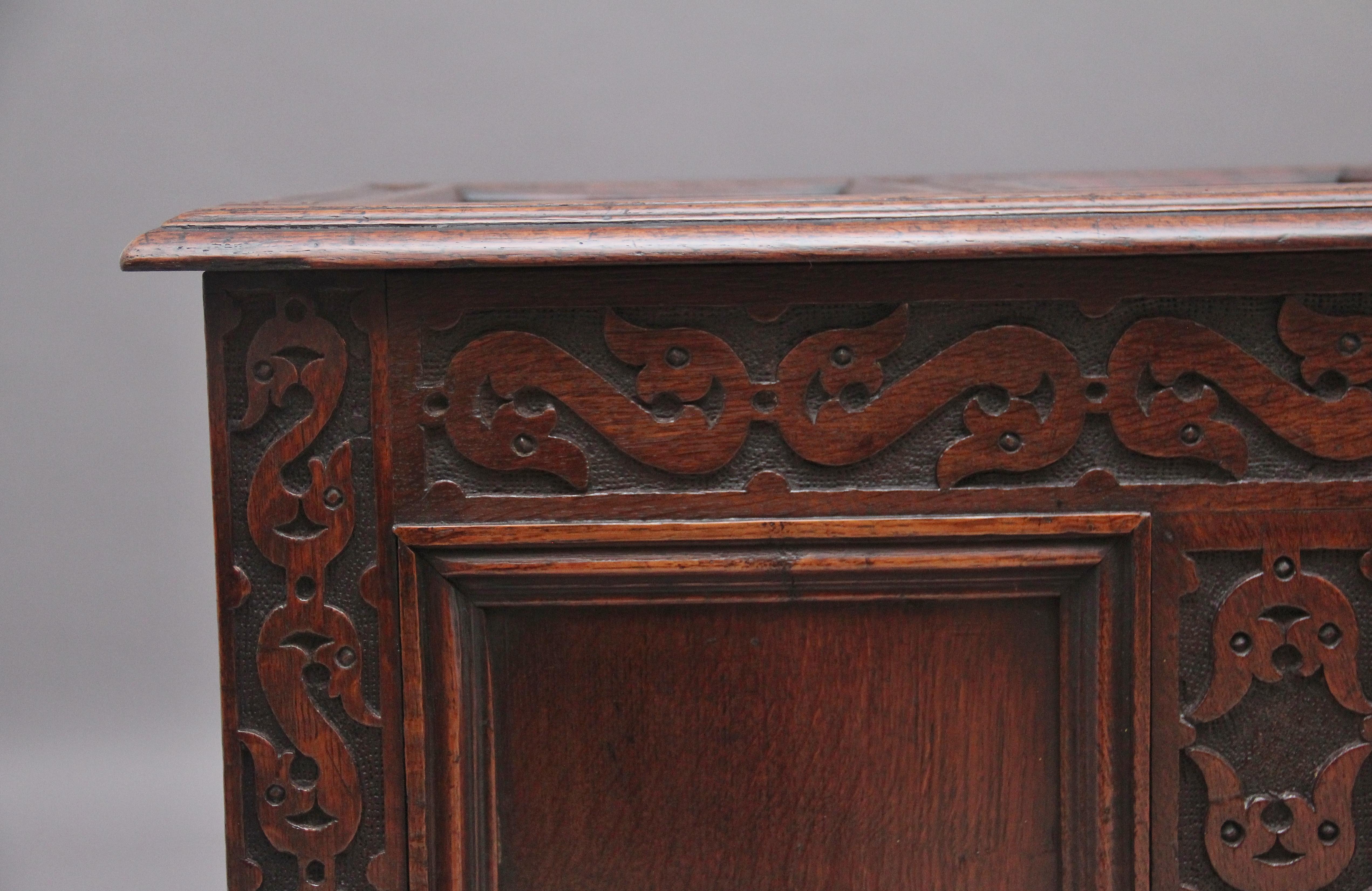 18th Century oak coffer with the moulded edge hinged four panelled top opening to reveal a large compartment space, the three panelled front having wonderful decorative carving, panelled sides, standing on square legs. This coffer has a lovely warm